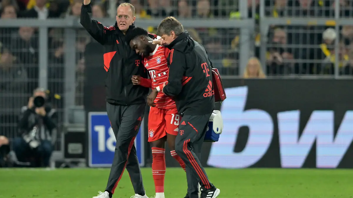 08.10.2022, Nordrhein-Westfalen, Dortmund: Fußball: Bundesliga, Borussia Dortmund - FC Bayern München, 9. Spieltag, Signal Iduna Park. Münchens Alphonso Davies (M) wird nach einer Verletzung vom Platz geführt. WICHTIGER HINWEIS: Gemäß den Vorgaben der DFL Deutsche Fußball Liga bzw. des DFB Deutscher Fußball-Bund ist es untersagt, in dem Stadion und/oder vom Spiel angefertigte Fotoaufnahmen in Form von Sequenzbildern und/oder videoähnlichen Fotostrecken zu verwerten bzw. verwerten zu lassen. Foto: David Inderlied/dpa +++ dpa-Bildfunk +++