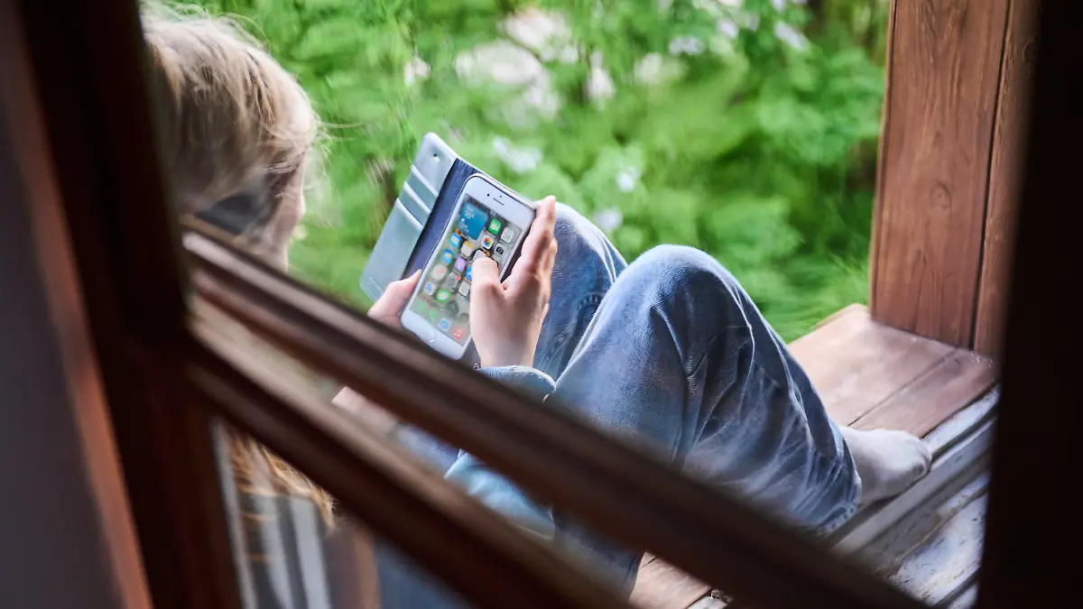 ARCHIV - 28.05.2022, Berlin: Ein Junge sitzt am Fenster und schaut auf sein Handy. Frankreich will eine Altersgrenze von 13 Jahren für soziale Medien einführen. (zu dpa: «Frankreichs Premier will Altersgrenze von 13 Jahren für soziale Medien») Foto: Annette Riedl/dpa +++ dpa-Bildfunk +++