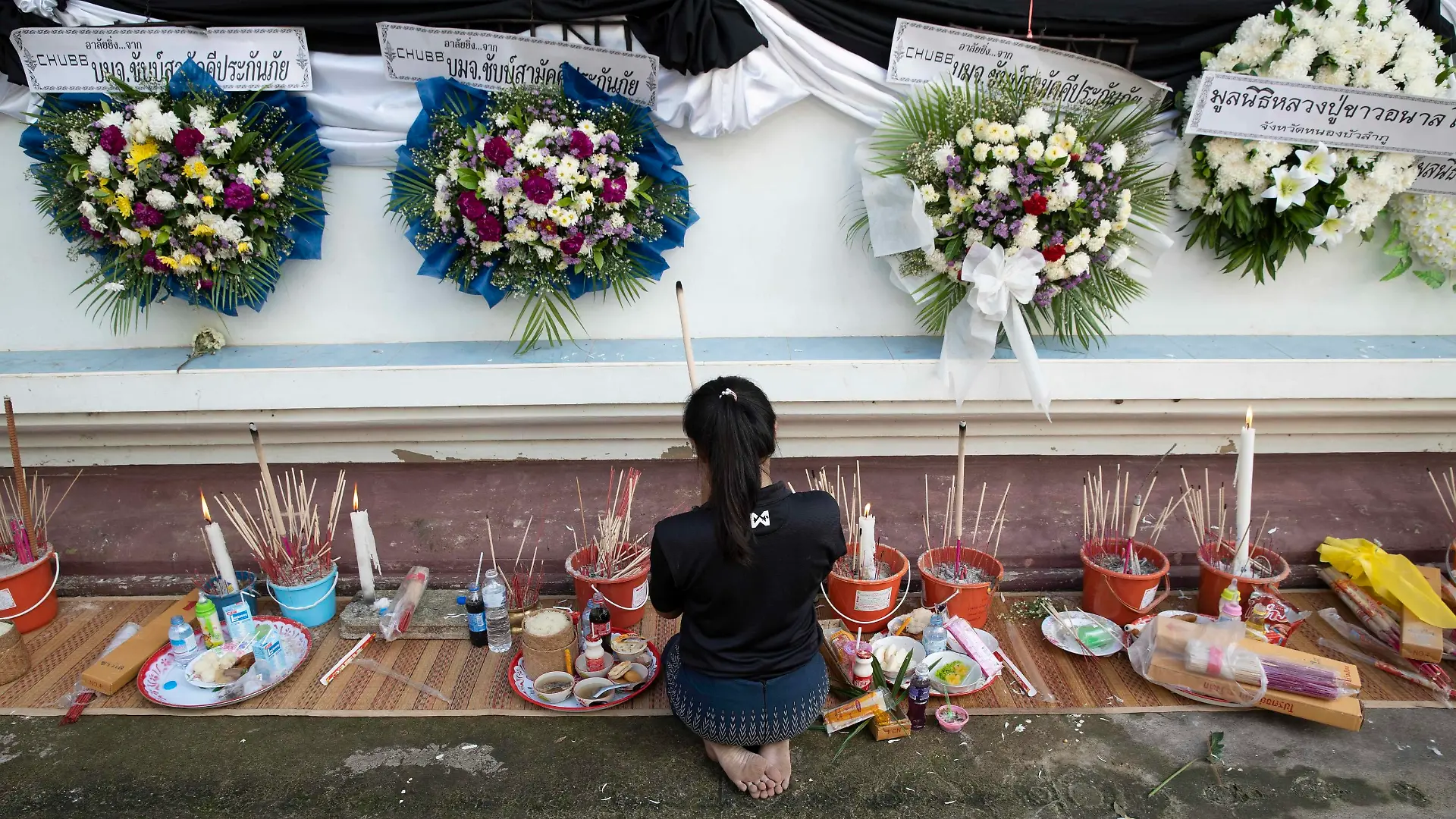 October 8, 2022, Uthai Sawan, Nong Bua Lamphu, Thailand: Ms. Panadda, 27 years old, lights incense and prays outside of Wat Rat Samakee temple in Nong Bua Lamphu province, Thailand while funeral rites for 6 of her family members take place inside, killed during the Uthai Sawan day care center massacre. An assailant used a combination of guns and knives to kill at least 35 people at the day care center, most of the victims being young children. Uthai Sawan Thailand - ZUMAt128 20221008_zap_t128_025 Copyright: xAdryelxTalamantesx
