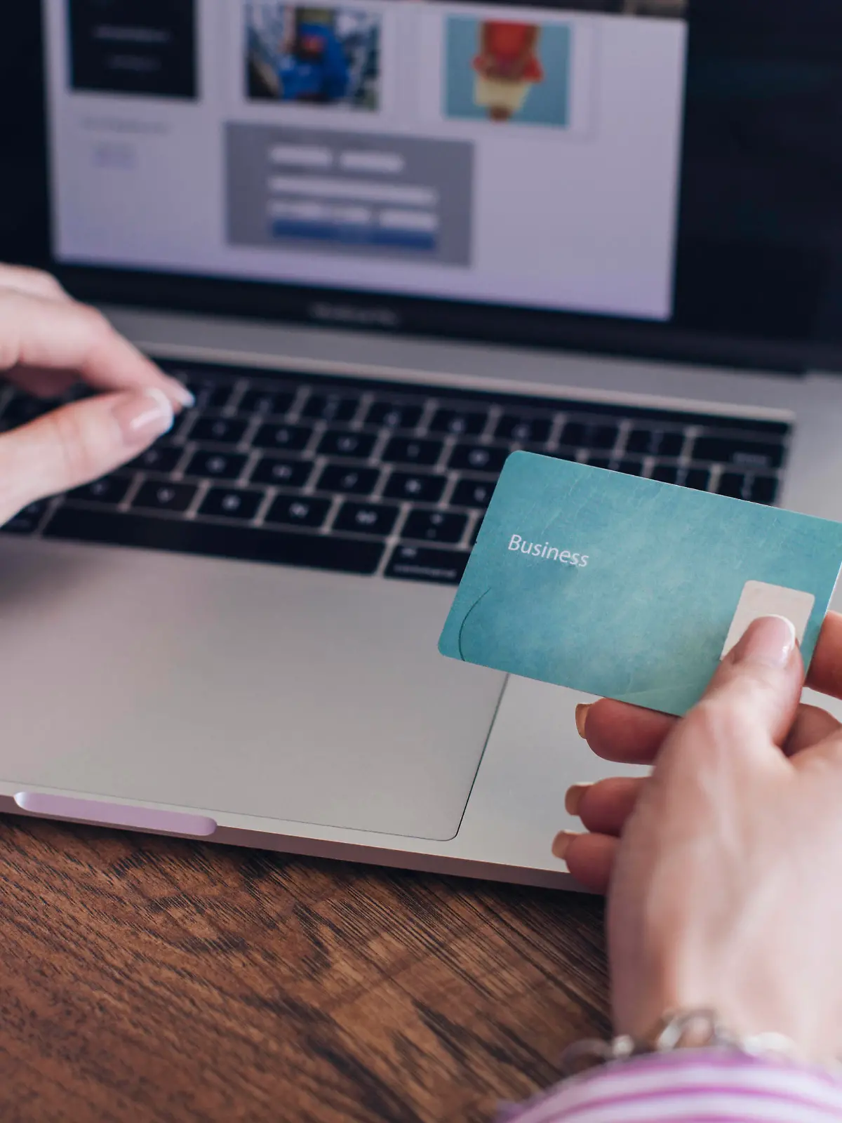  Cropped hands of businesswoman holding credit card doing online shopping over laptop in office model released Symbolfoto property released MOMF00879