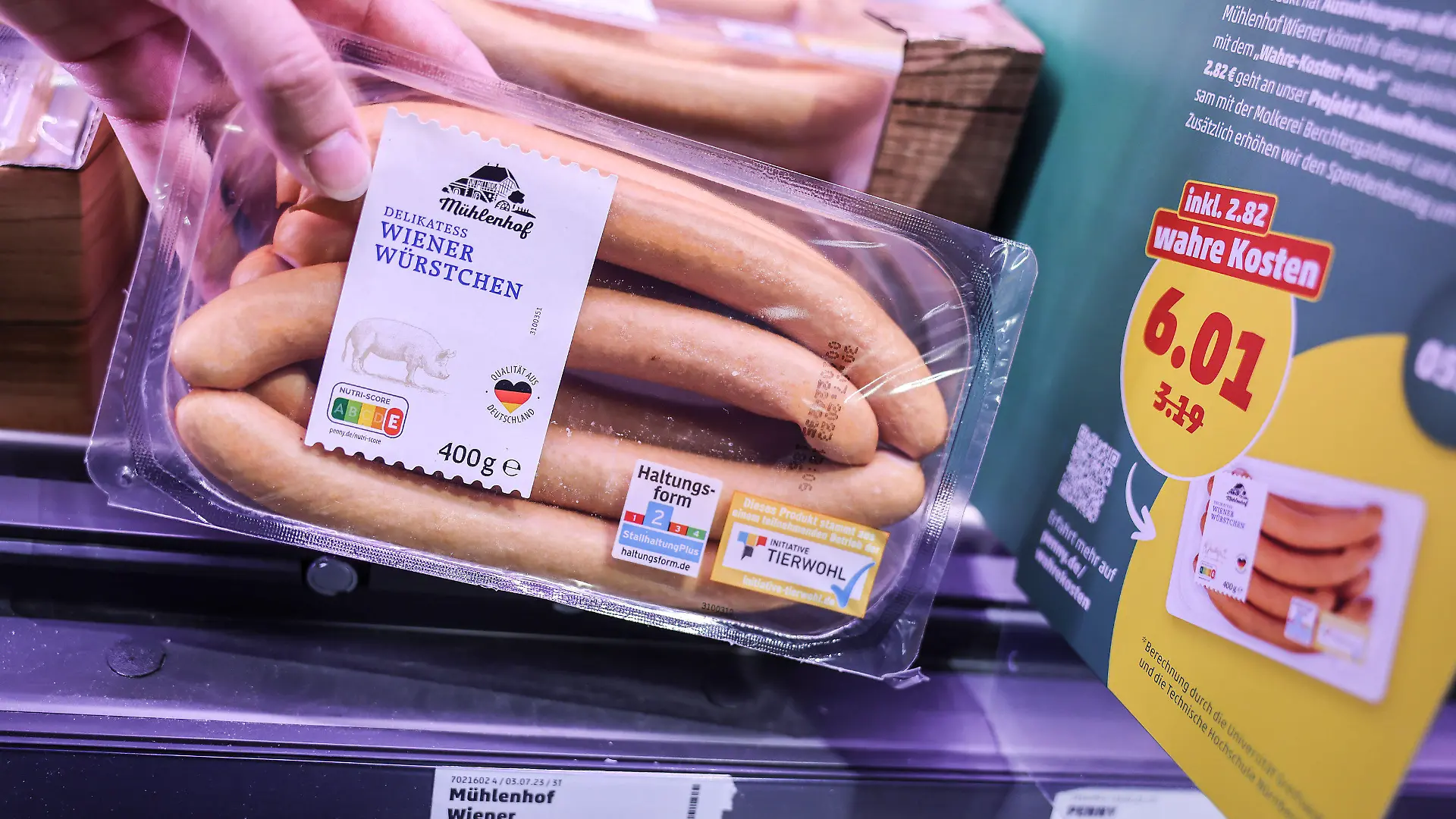 PRODUKTION - 26.07.2023, Nordrhein-Westfalen, Köln: Zwei Preisschilder hängen im Kühlregal vor einer Packung mit Wiener Würstchen. Penny sorgt ab Montag (31.0.07.2023) für einen Preisschock der eigenen Art. Für neun Produkte kassiert das Unternehmen die «wahren Preise». Dabei werden auch verdeckte Kosten etwa für Umweltverschmutzung bei der Produktion berücksichtigt. (Zu dpa: "Discounter-Experiment: Wie teuer Lebensmittel eigentlich sei müssten") Foto: Oliver Berg/dpa +++ dpa-Bildfunk +++