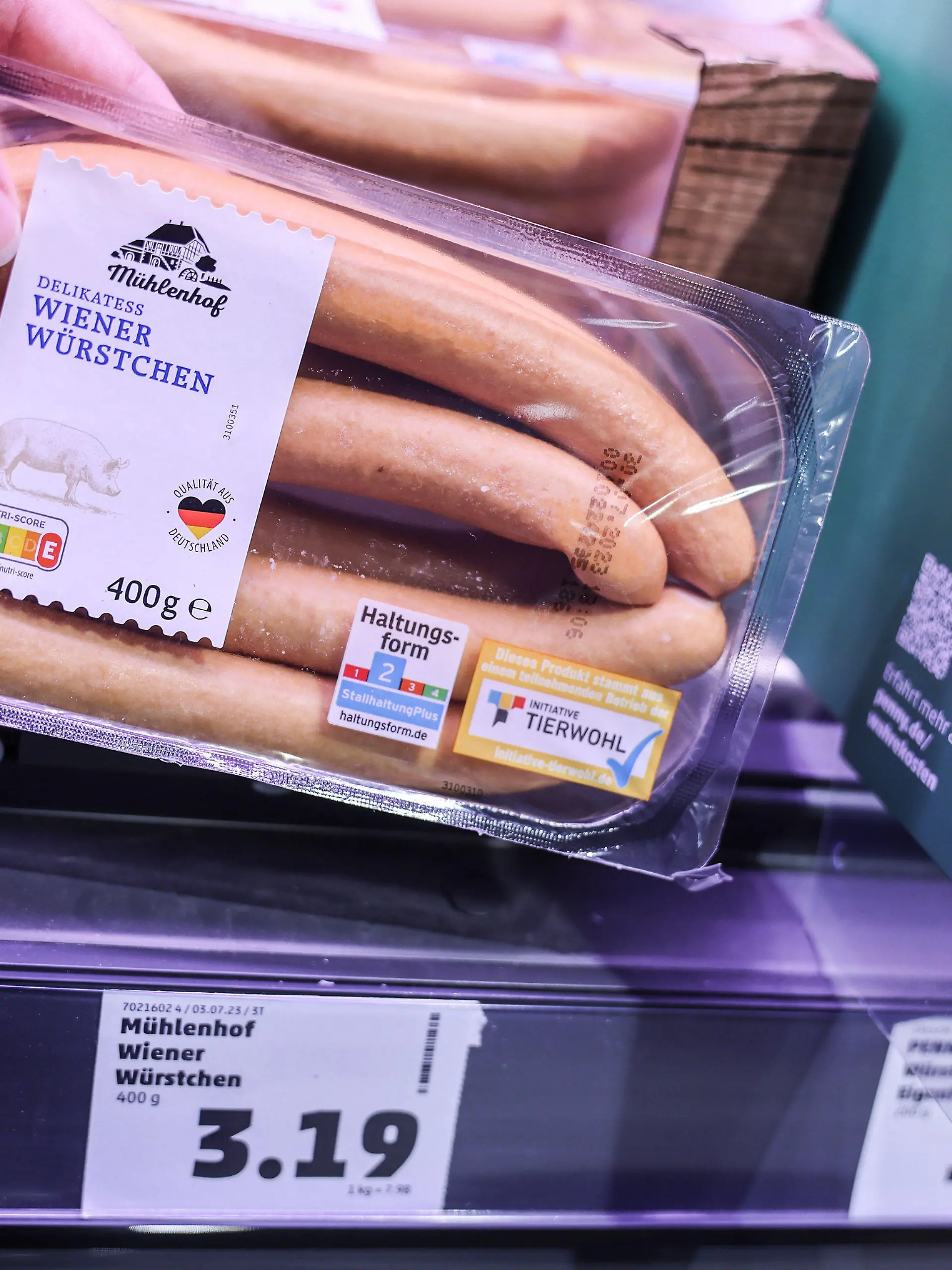 PRODUKTION - 26.07.2023, Nordrhein-Westfalen, Köln: Zwei Preisschilder hängen im Kühlregal vor einer Packung mit Wiener Würstchen. Penny sorgt ab Montag (31.0.07.2023) für einen Preisschock der eigenen Art. Für neun Produkte kassiert das Unternehmen die «wahren Preise». Dabei werden auch verdeckte Kosten etwa für Umweltverschmutzung bei der Produktion berücksichtigt. (Zu dpa: "Discounter-Experiment: Wie teuer Lebensmittel eigentlich sei müssten") Foto: Oliver Berg/dpa +++ dpa-Bildfunk +++