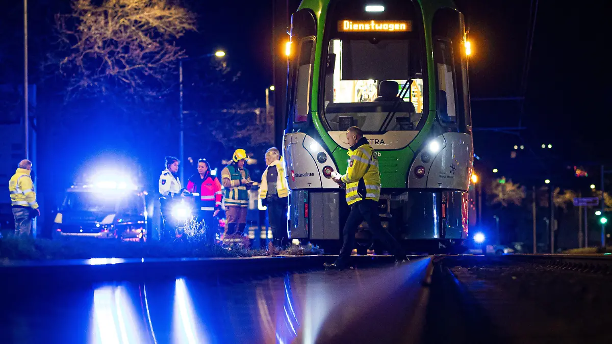 13.02.2024, Niedersachsen, Hannover: Einsatzkräfte stehen am Abend nach einem Unfall neben einer Stadtbahn. Eine Frau ist von der Stadtbahn erfasst und lebensgefährlich verletzt worden. Foto: Moritz Frankenberg/dpa +++ dpa-Bildfunk +++