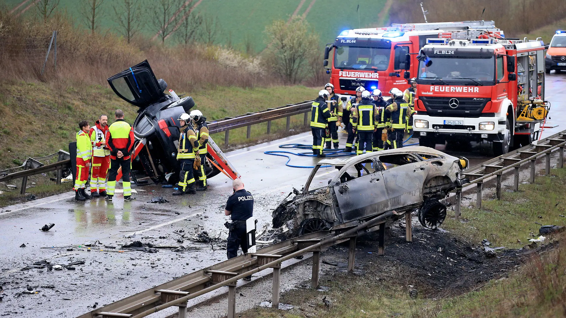 ARCHIV - 01.04.2023, Thüringen, Bad Langensalza: Ein ausgebrannter Pkw und ein weiteres verunfalltes Fahrzeug stehen an der Unfallstelle auf der B247. (zu dpa: «Angeklagter räumt Vorwürfe nach Unfall mit sieben Toten ein») Foto: Silvio Dietzel/dpa +++ dpa-Bildfunk +++