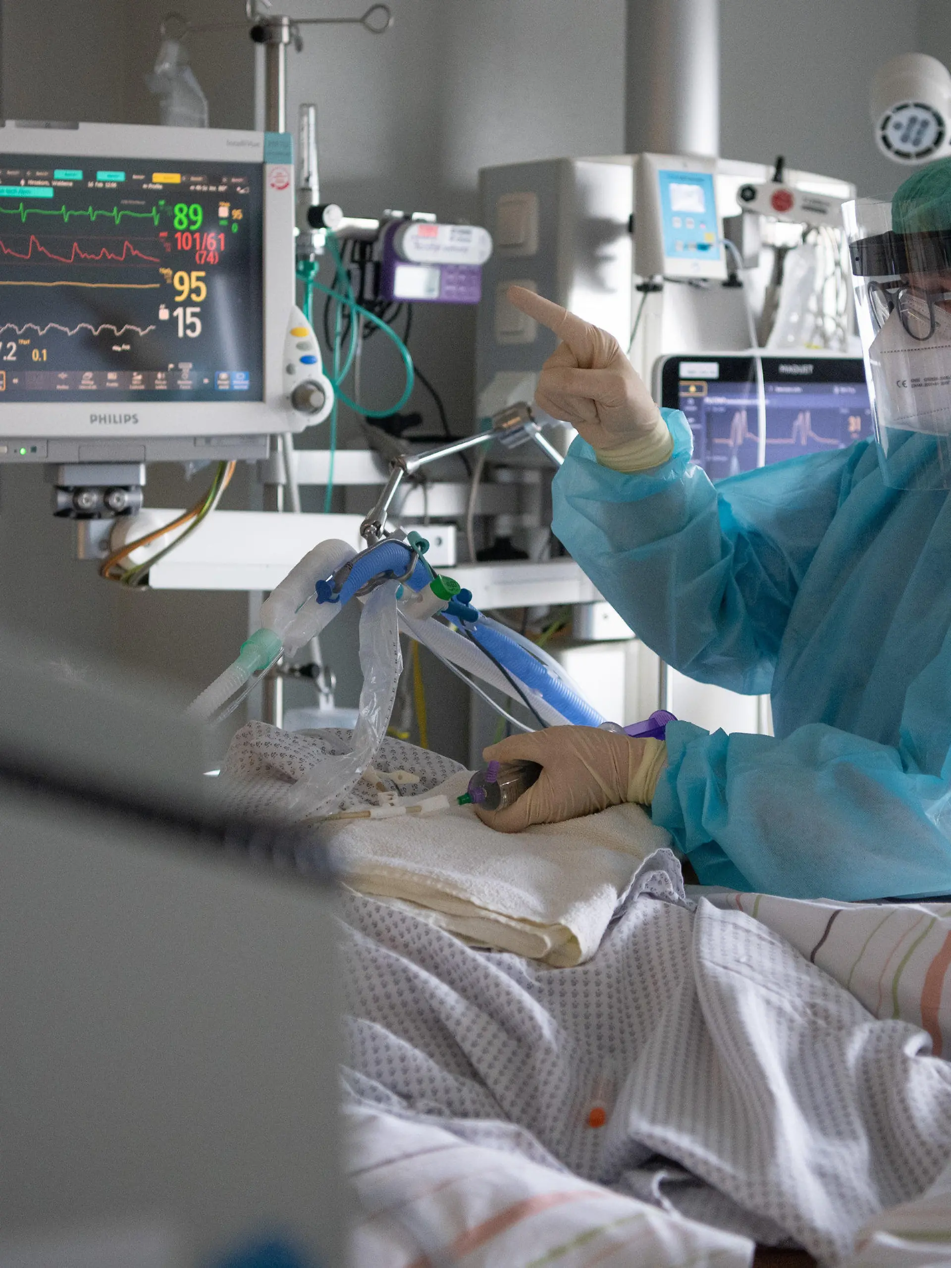 PRODUKTION - 16.02.2022, Hessen, Fulda: Eine Intensiv-Pflegerin versorgt einen schwer an Corona erkrankten Patienten auf der Intensivstation des Klinikums in Fulda. Viele Patienten mit schweren Verläufen liegen mehrere Wochen auf der Intensivstation, rund die Hälfte der künstlich beatmeten Patienten stirbt. (zu dpa "Sorgen um Engpässe in Kliniken und Altenheimen wegen Impfpflicht") Foto: Boris Roessler/dpa +++ dpa-Bildfunk +++