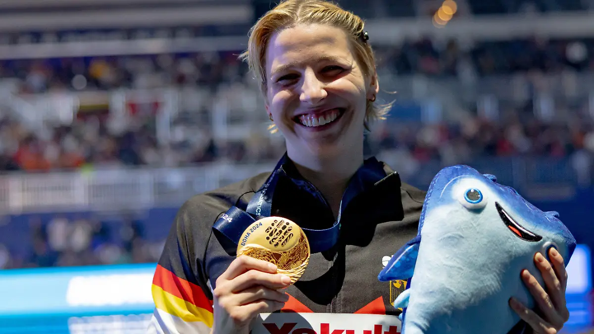 12.02.2024, Katar, Doha: Schwimmen: Weltmeisterschaft, 100 m Schmetterling, Frauen. Angelina Köhler aus Deutschland zeigt ihre Goldmedaille. (zu dpa: «Früher gemobbt, jetzt Weltmeisterin: Köhlers Schwimm-Triumph») Foto: Jo Kleindl/dpa +++ dpa-Bildfunk +++