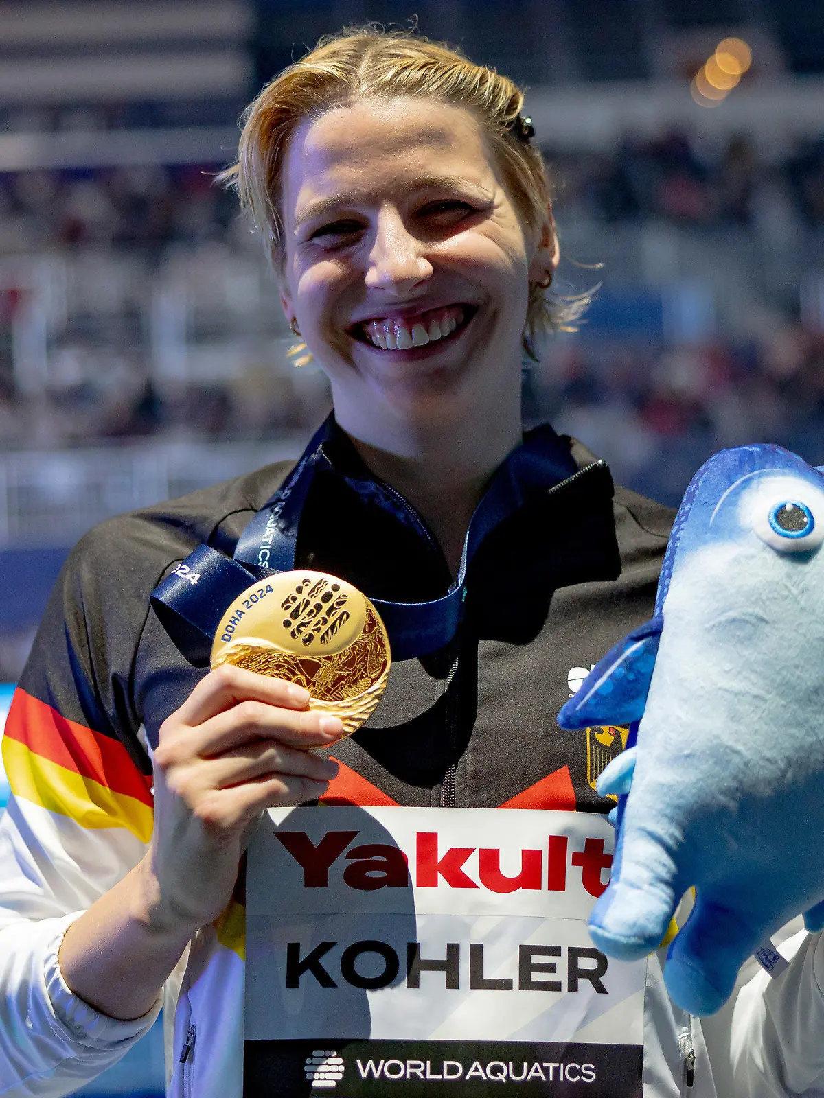 12.02.2024, Katar, Doha: Schwimmen: Weltmeisterschaft, 100 m Schmetterling, Frauen. Angelina Köhler aus Deutschland zeigt ihre Goldmedaille. (zu dpa: «Früher gemobbt, jetzt Weltmeisterin: Köhlers Schwimm-Triumph») Foto: Jo Kleindl/dpa +++ dpa-Bildfunk +++