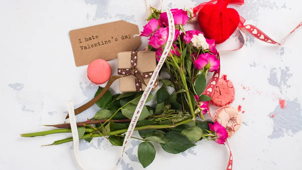 I hate Valentines day concept. After party mess with flowers, gift box, cookies and decorative hearts. Top view. Space for text