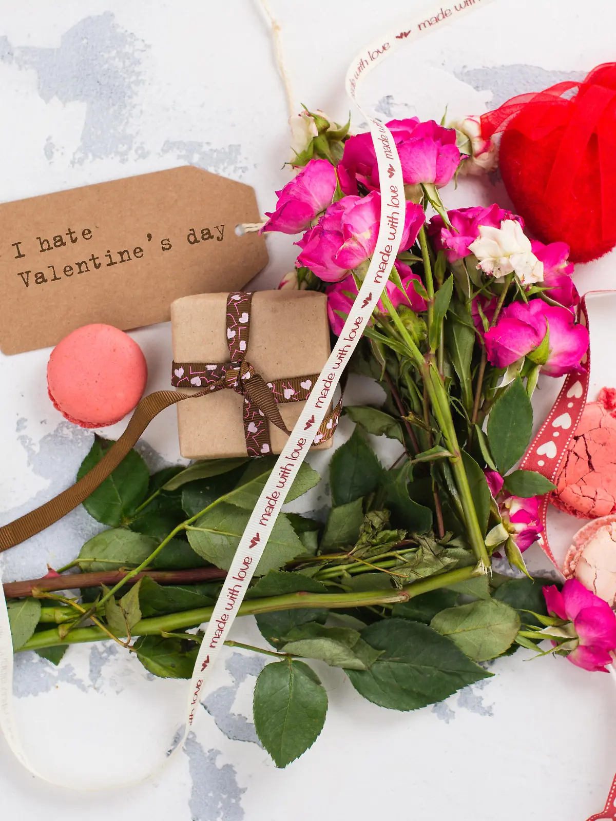 I hate Valentines day concept. After party mess with flowers, gift box, cookies and decorative hearts. Top view. Space for text