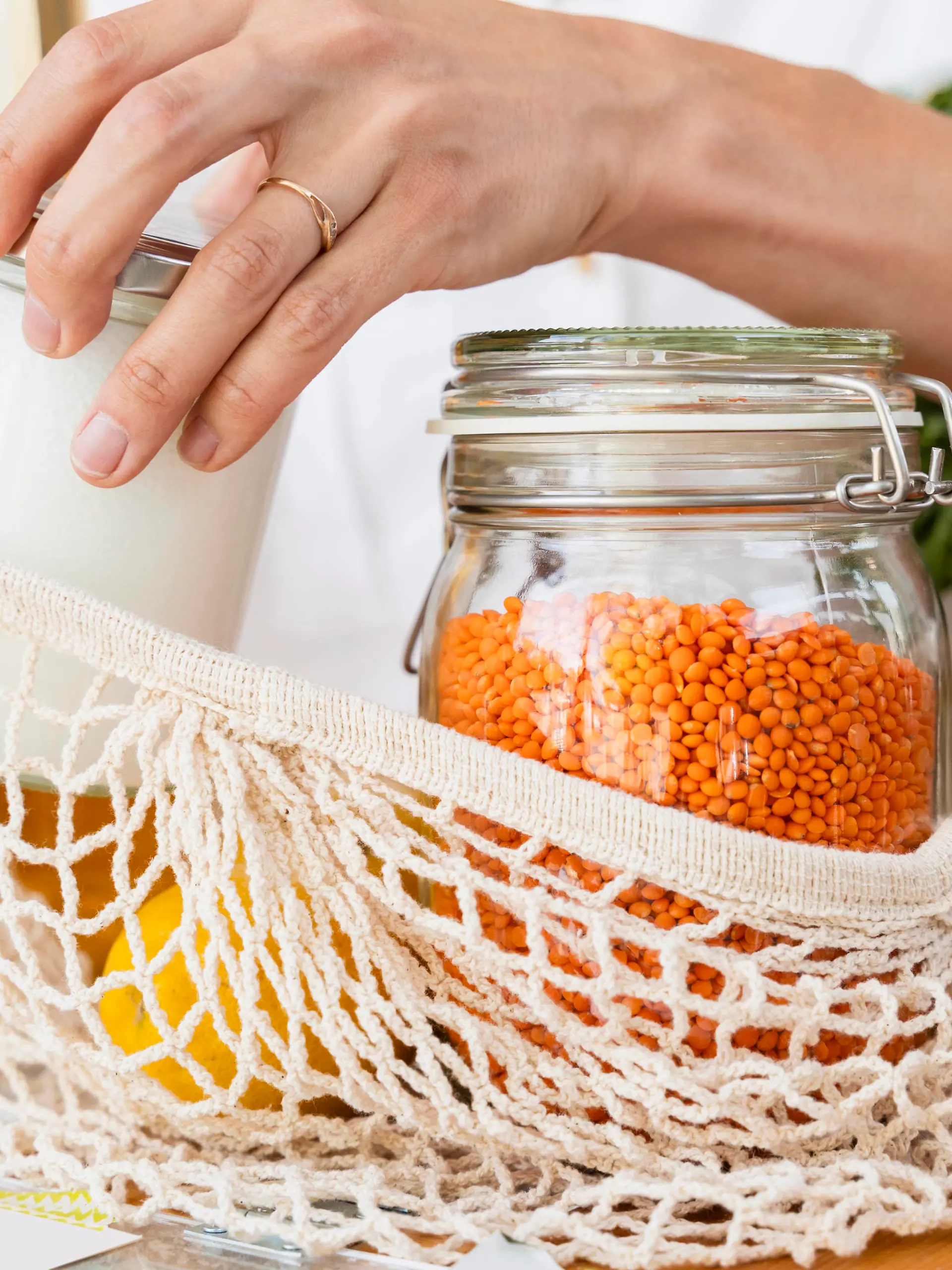 Woman putting jars in mesh bag at table model released, Symbolfoto property released, NDEF01103