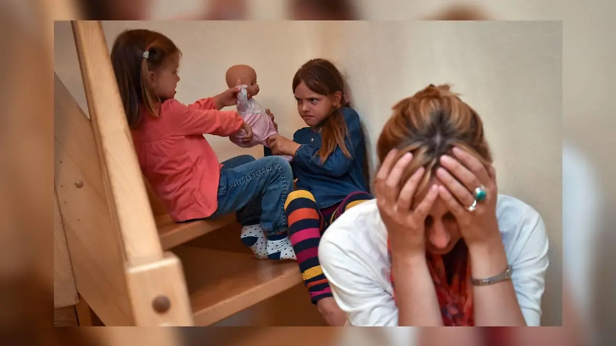 ILLUSTRATION - Gestresst sitzt eine Mutter am 16.06.2014 auf einer Treppe in ihrem Haus in Sieversdorf (Brandenburg), während sich dahinter ihre beiden Kinder um eine Puppe streiten. Die Krankenkasse DAK-Gesundheit stellt am 17.06.2014 eine Studie zu
