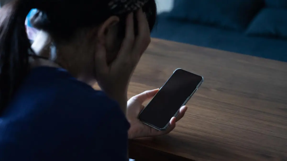 A woman who is frightened by a call coming from her phone.
She is holding her phone in a dark room.
A stalker on a social networking site.
Japanese female model.