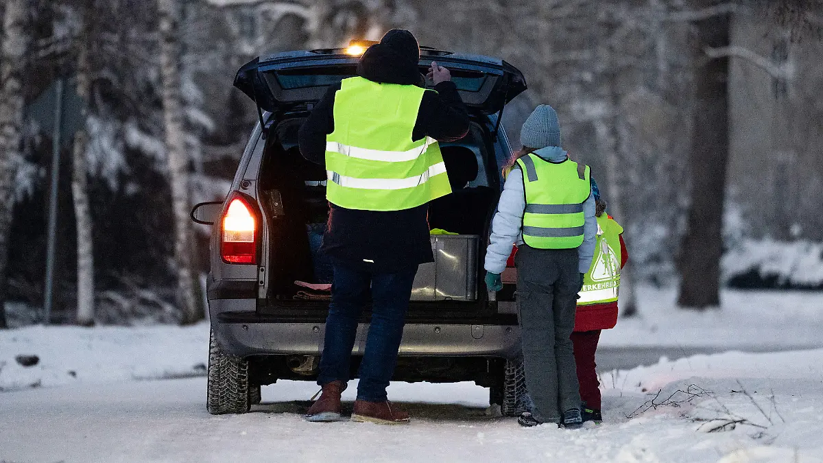 Kind und Elternteil mit Warnweste am Auto
