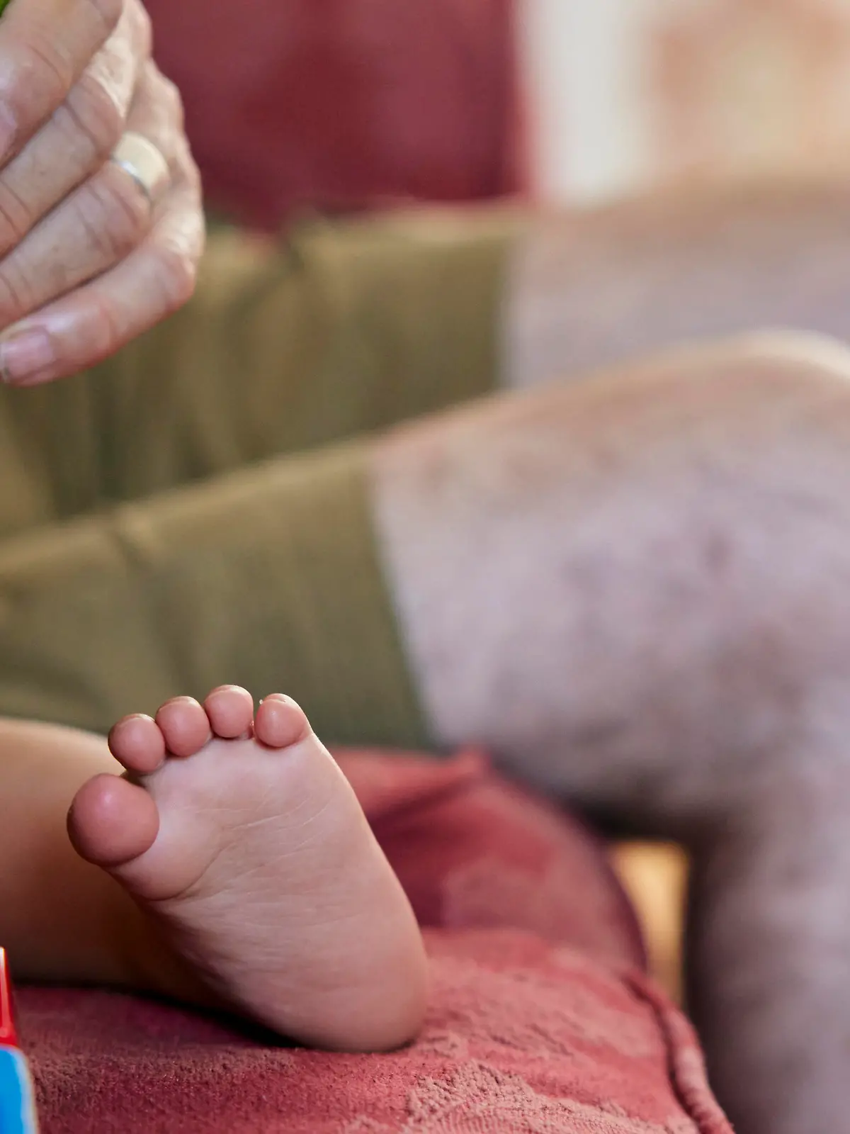 Close up of grandfather reading to toddler, view of the child's bare feet and grandpa's knees. || Modellfreigabe vorhanden / Mindestpreis 20 Euro 