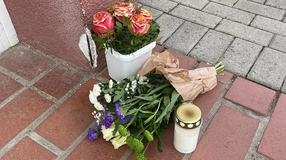Vor dem Kindergarten drücken Menschen durch Blumen ihre Anteilnahme aus