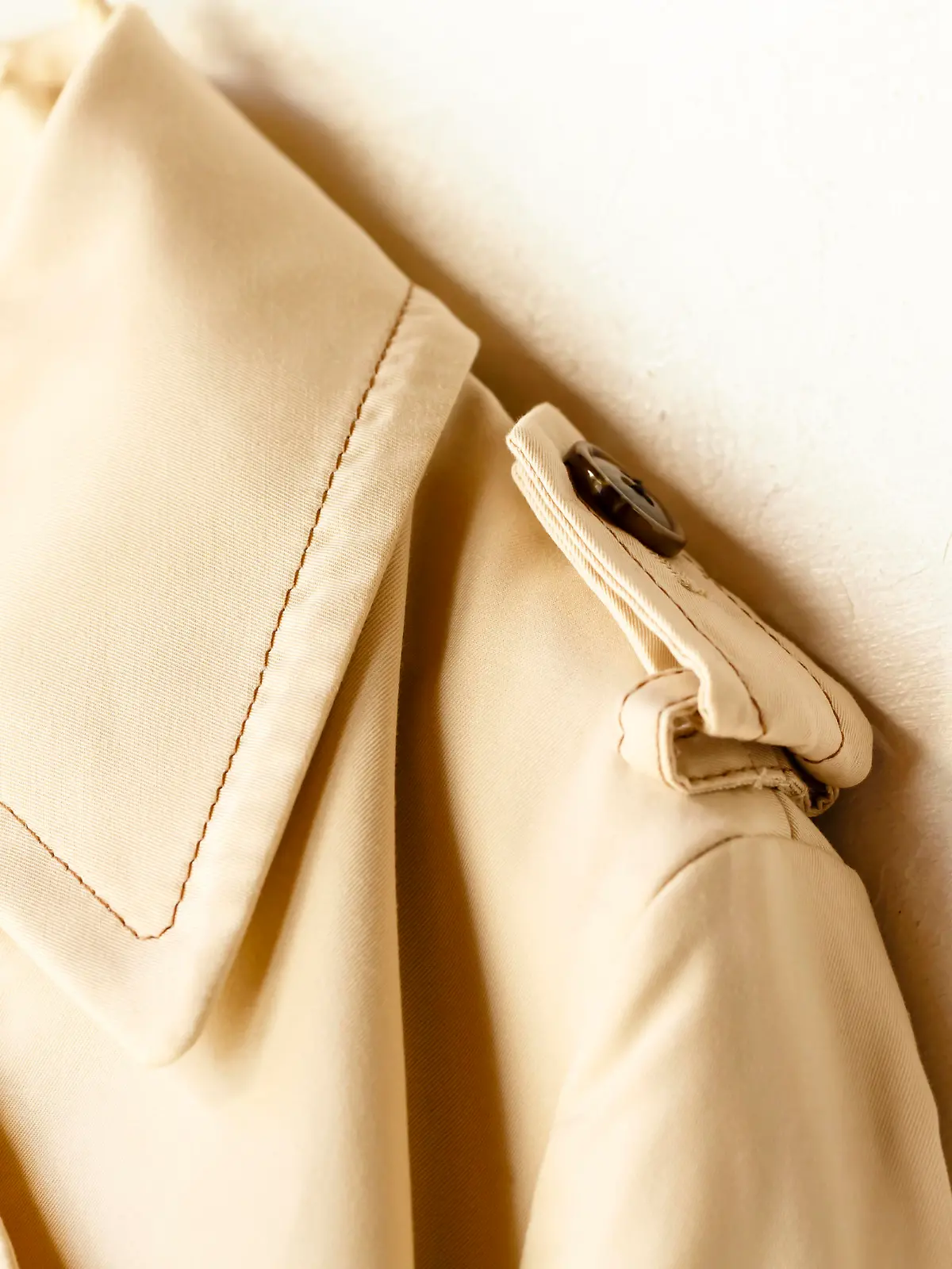 A beige elegant trench coat isolated over white. Close up