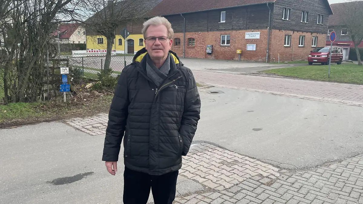 Ein Mann steht auf der Straße und schaut in die Kamera.