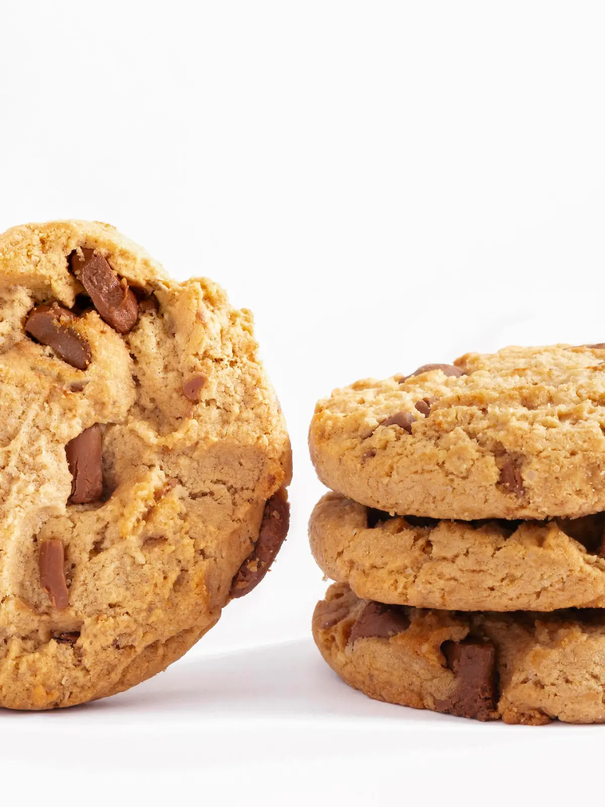 Chocolate chip cookies stacked on white background.