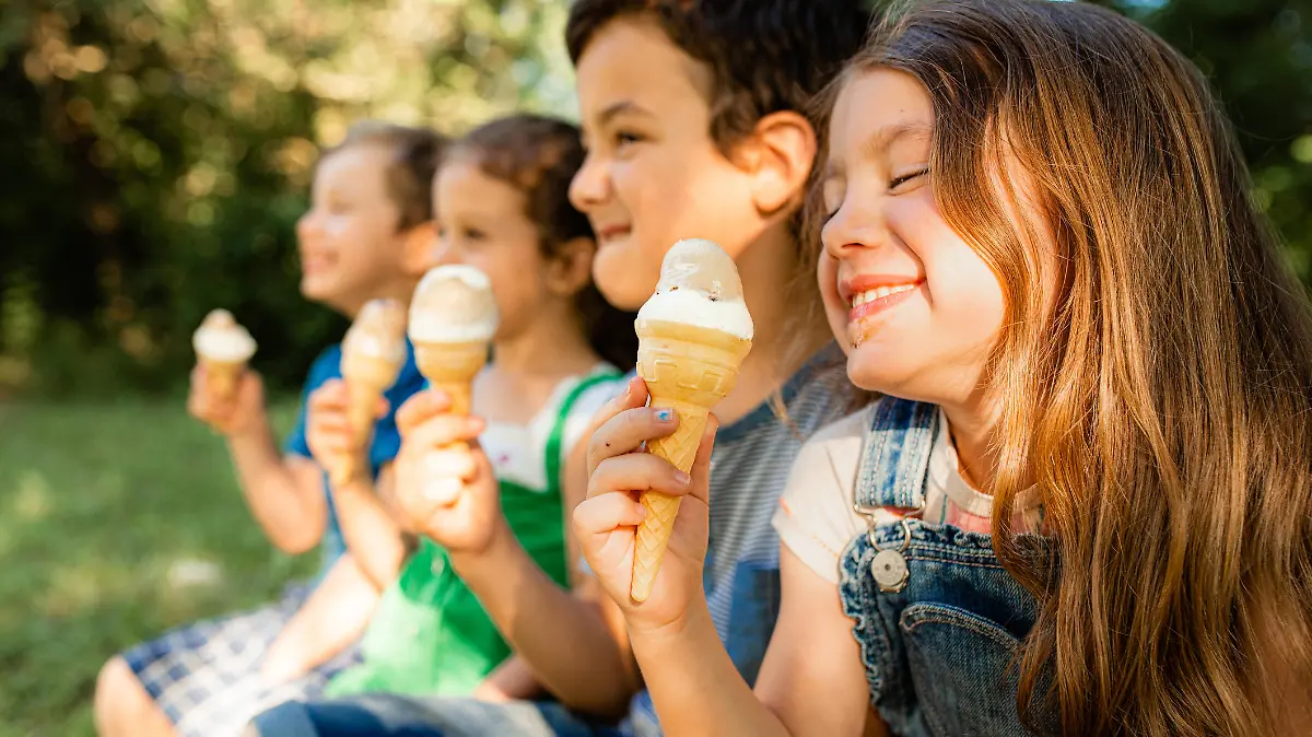 Group of children having fun licking ice cream cone in the yard