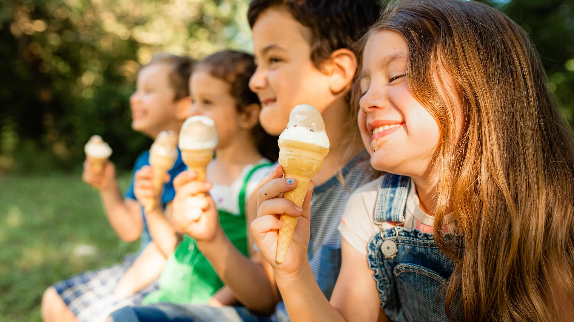Group of children having fun licking ice cream cone in the yard