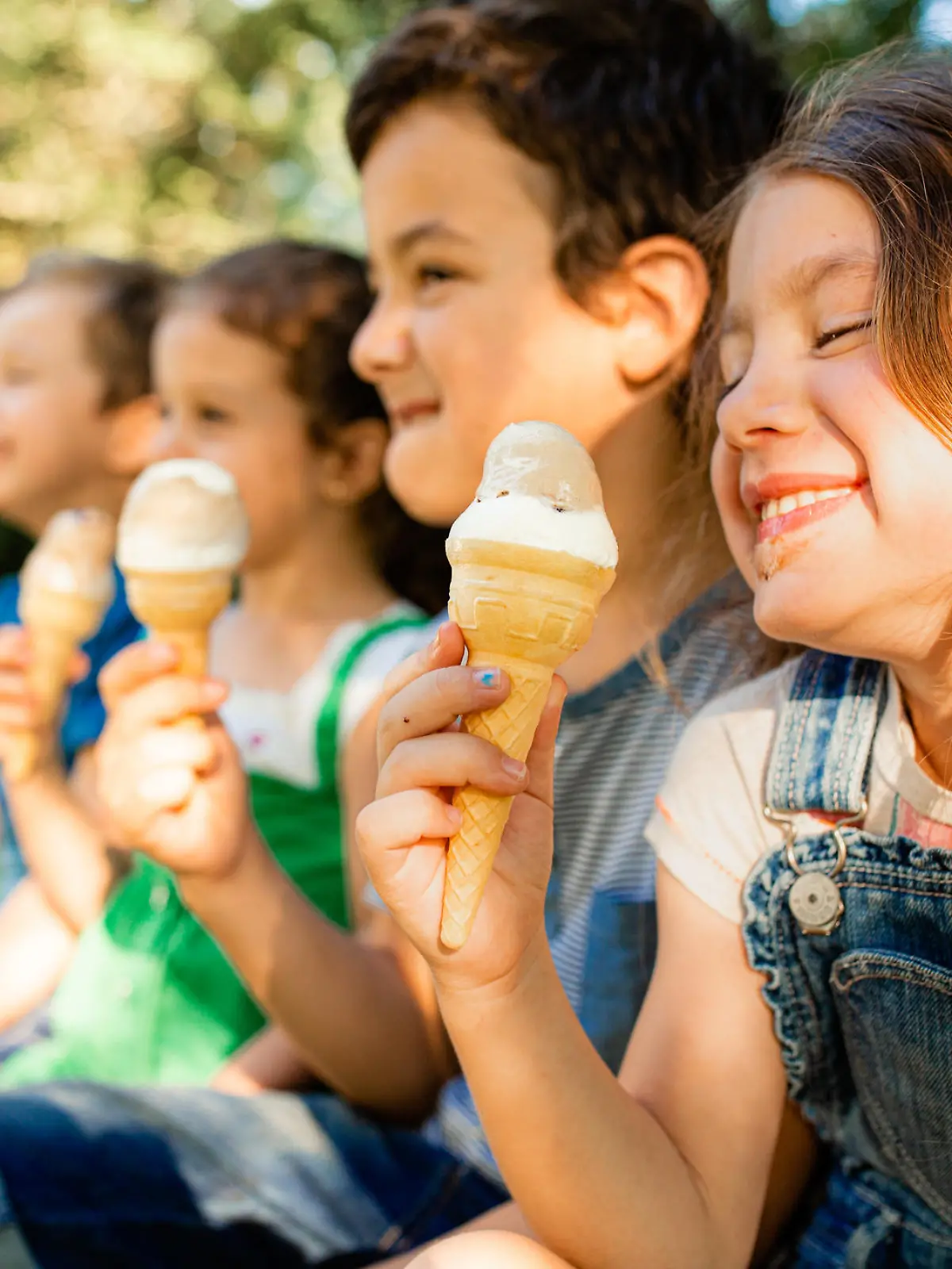 Group of children having fun licking ice cream cone in the yard