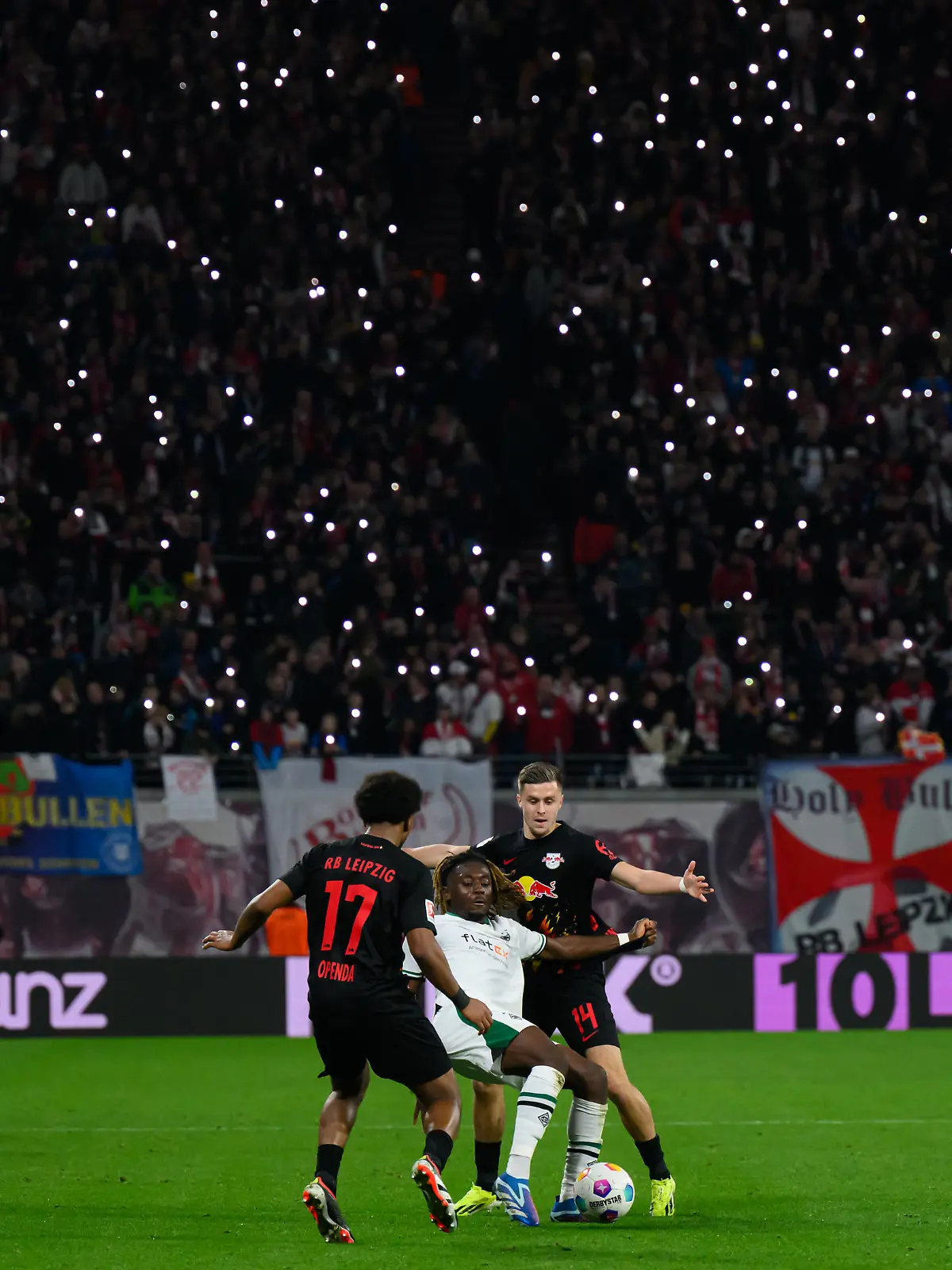 Fußball: Bundesliga, RB Leipzig - Borussia Mönchengladbach, 22. Spieltag, Red Bull Arena. Leipzigs Lois Openda (l) und Christoph Baumgartner (r) gegen Mönchengladbachs Manu Koné.