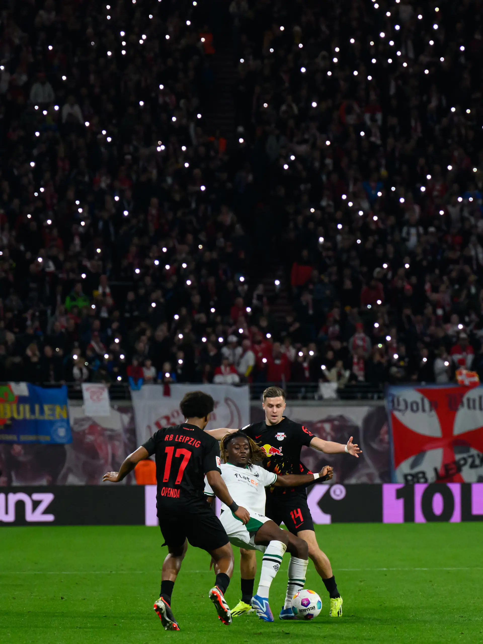 Fußball: Bundesliga, RB Leipzig - Borussia Mönchengladbach, 22. Spieltag, Red Bull Arena. Leipzigs Lois Openda (l) und Christoph Baumgartner (r) gegen Mönchengladbachs Manu Koné.