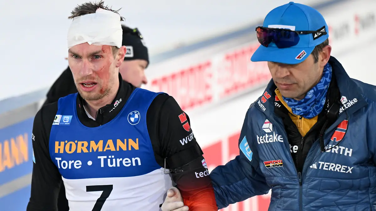 18.02.2024, Tschechien, Nove Mesto Na Morave: Biathlon, Weltmeisterschaft, Massenstart 15 km, Männer. DSV-Arzt Jan Wüstenfeld (r) versorgt im Ziel den am Kopf verletzten Johannes Kühn aus Deutschland. Foto: Hendrik Schmidt/dpa +++ dpa-Bildfunk +++