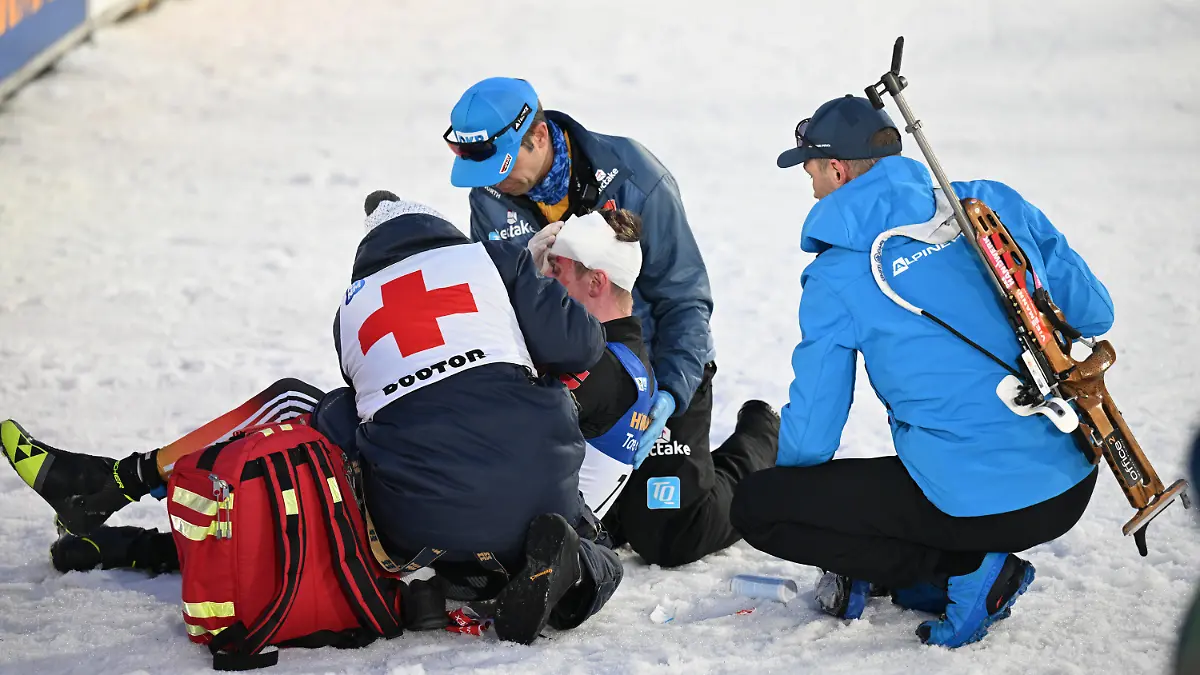 18.02.2024, Tschechien, Nove Mesto Na Morave: Biathlon, Weltmeisterschaft, Massenstart 15 km, Männer. DSV-Arzt Jan Wüstenfeld (2.v.r.) versorgt im Ziel den am Kopf verletzten Johannes Kühn aus Deutschland. Foto: Hendrik Schmidt/dpa +++ dpa-Bildfunk +++