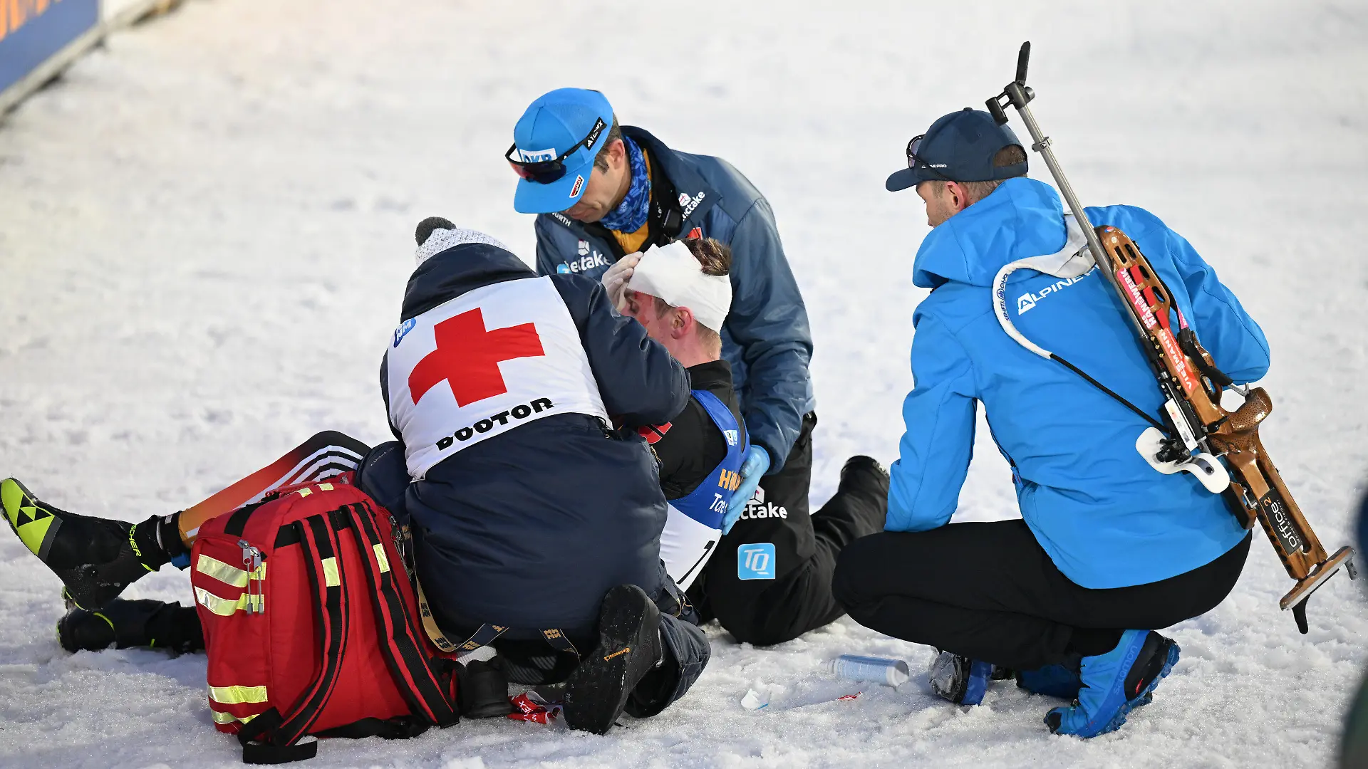 18.02.2024, Tschechien, Nove Mesto Na Morave: Biathlon, Weltmeisterschaft, Massenstart 15 km, Männer. DSV-Arzt Jan Wüstenfeld (2.v.r.) versorgt im Ziel den am Kopf verletzten Johannes Kühn aus Deutschland. Foto: Hendrik Schmidt/dpa +++ dpa-Bildfunk +++