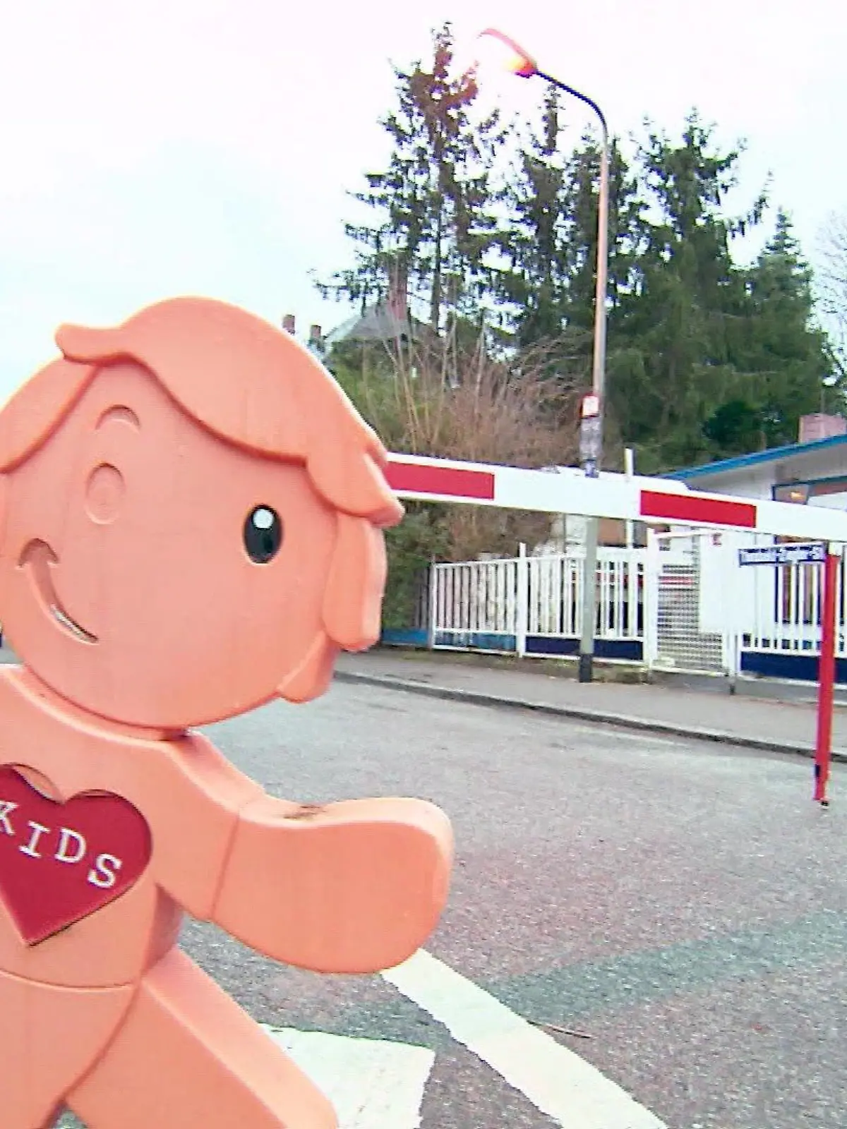 Eine Schranke im Hintergrund mit einer Kinderfigur im Vordergrund