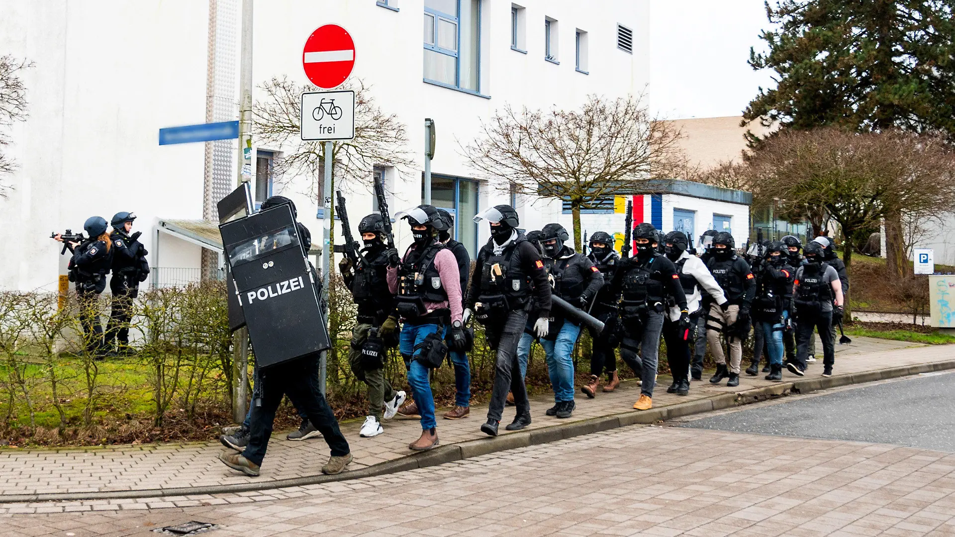 19.02.2024, Schleswig-Holstein, Mölln: Polizisten einer Spezialeinheit gehen an einem Gebäude einer Berufsschule vorbei. Nachdem am Vormittag auf dem Gelände eine Person mit einer Waffe gesehen worden sein soll, ist die Polizei im Einsatz. Foto: Daniel Bockwoldt/dpa +++ dpa-Bildfunk +++