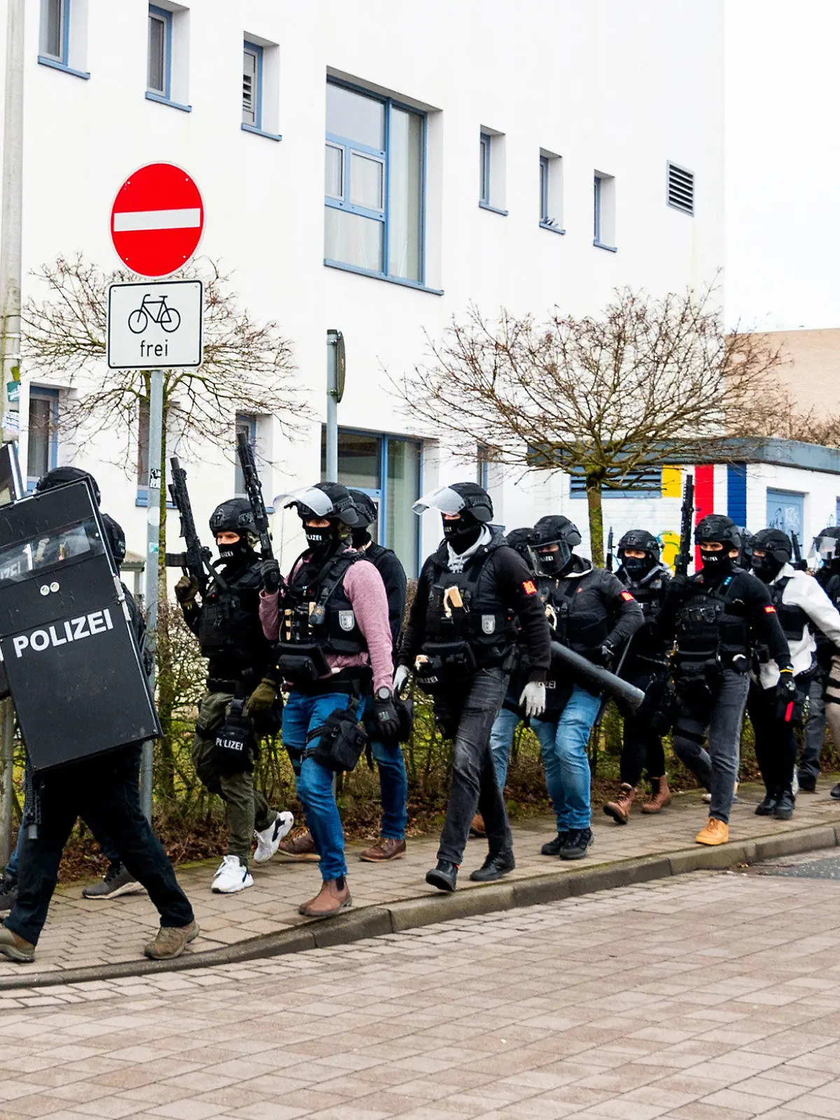 19.02.2024, Schleswig-Holstein, Mölln: Polizisten einer Spezialeinheit gehen an einem Gebäude einer Berufsschule vorbei. Nachdem am Vormittag auf dem Gelände eine Person mit einer Waffe gesehen worden sein soll, ist die Polizei im Einsatz. Foto: Daniel Bockwoldt/dpa +++ dpa-Bildfunk +++
