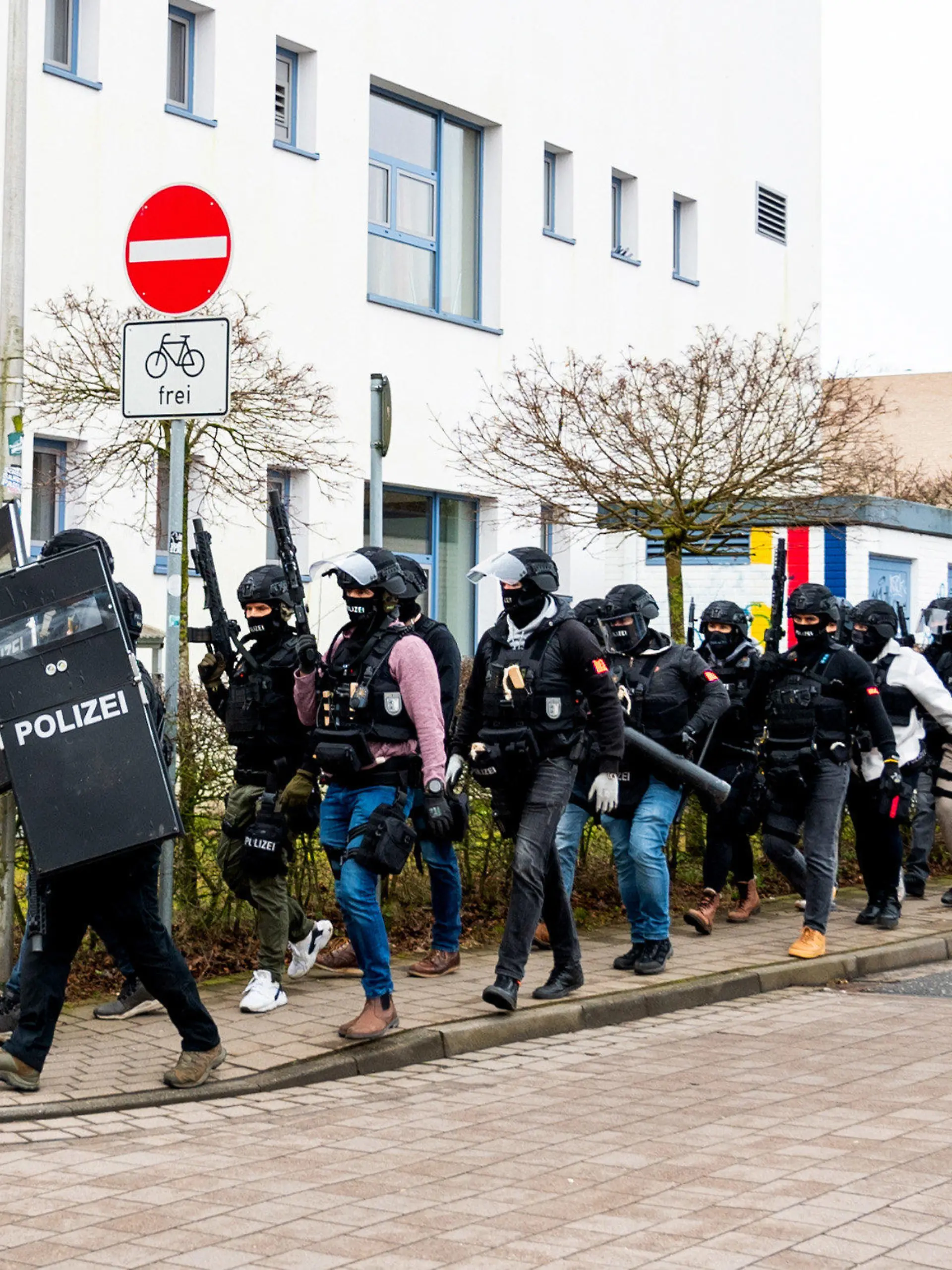 19.02.2024, Schleswig-Holstein, Mölln: Polizisten einer Spezialeinheit gehen an einem Gebäude einer Berufsschule vorbei. Nachdem am Vormittag auf dem Gelände eine Person mit einer Waffe gesehen worden sein soll, ist die Polizei im Einsatz. Foto: Daniel Bockwoldt/dpa +++ dpa-Bildfunk +++