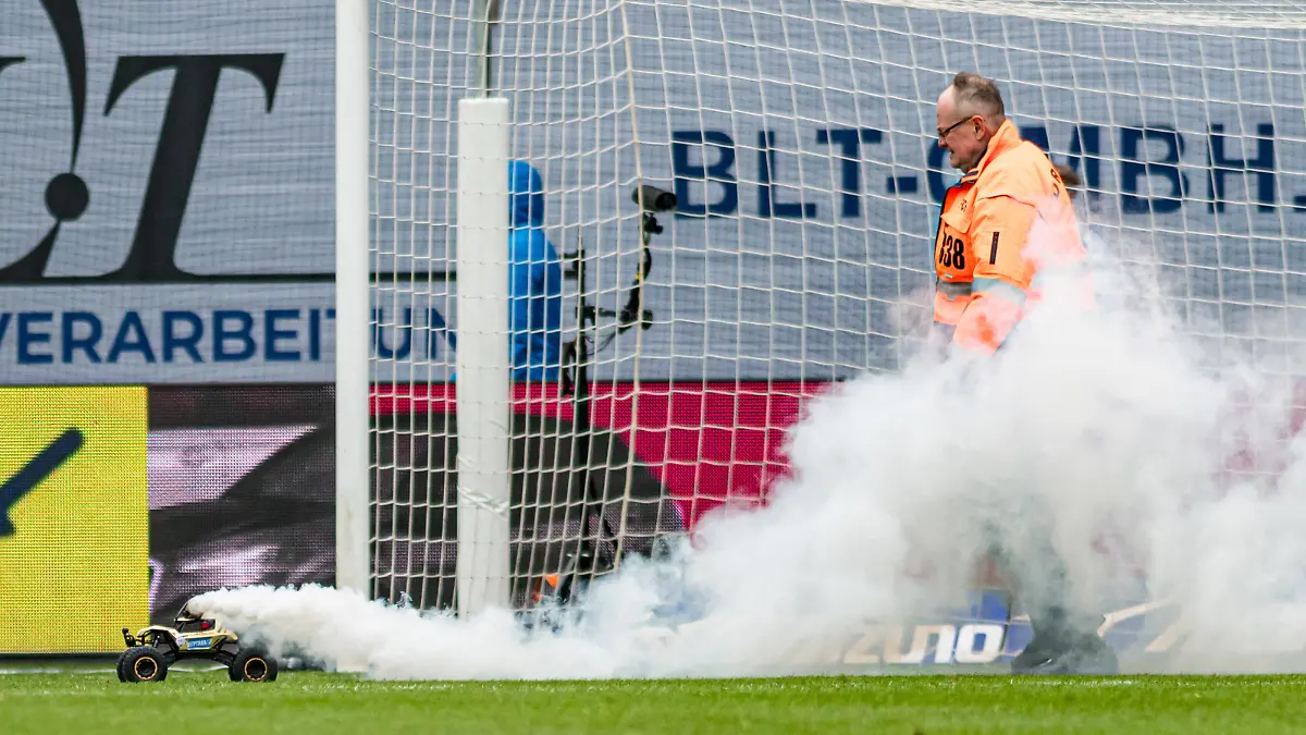 Rostock, Deutschland 17. Februar 2024: 2. BL - 2023/2024 - FC Hansa Rostock vs. Hamburger SV Im Bild: ferngesteuertes Auto mit weissem Rauch auf dem Spielfeld - gejagt von einem ordner - protest gegen investoren dfl /// DFL regulations prohibit any use of photographs as image sequences and/or quasi-video. ///