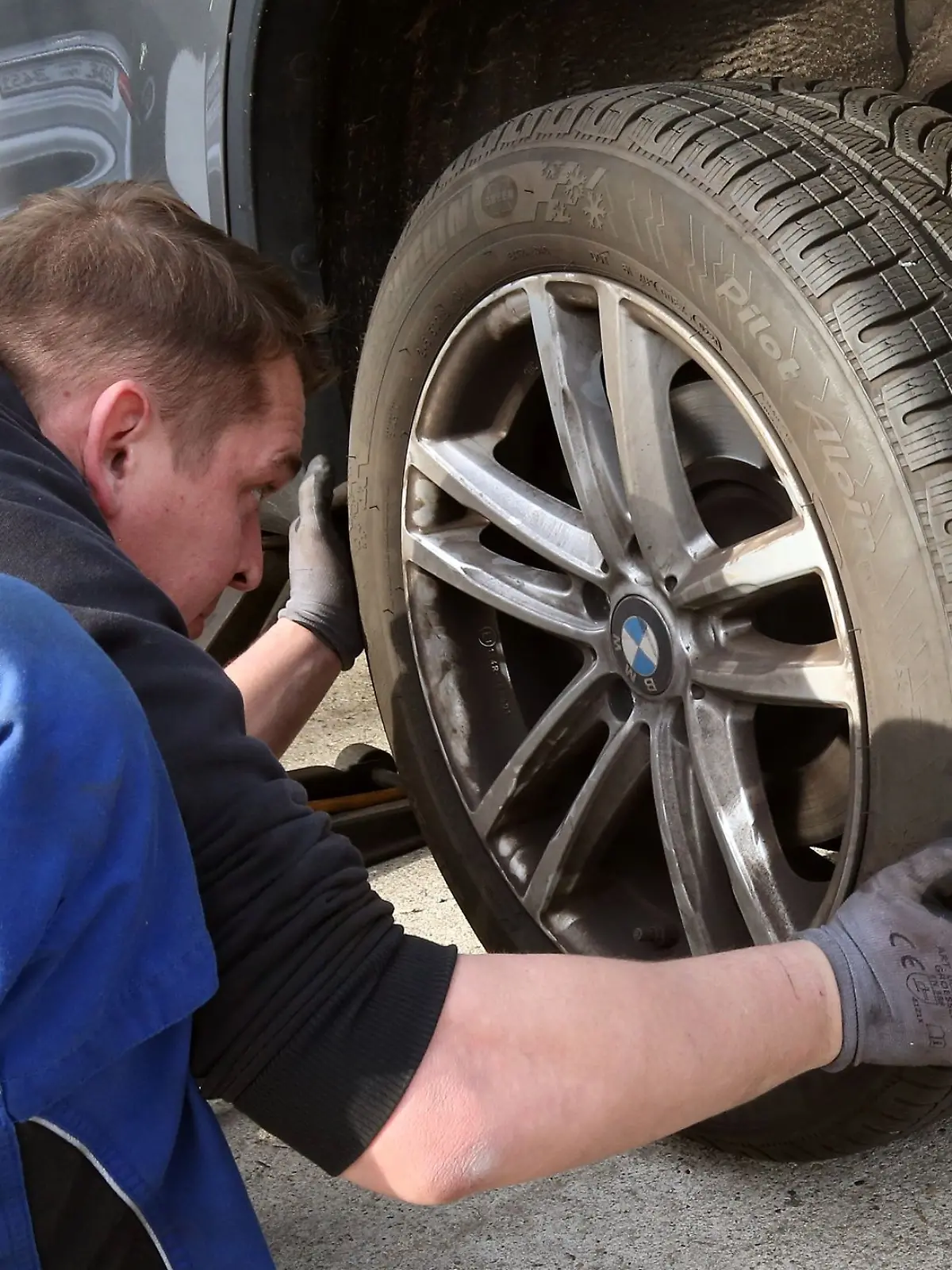 Ein Monteur wechselt an einem Fahrzeug Reifen.