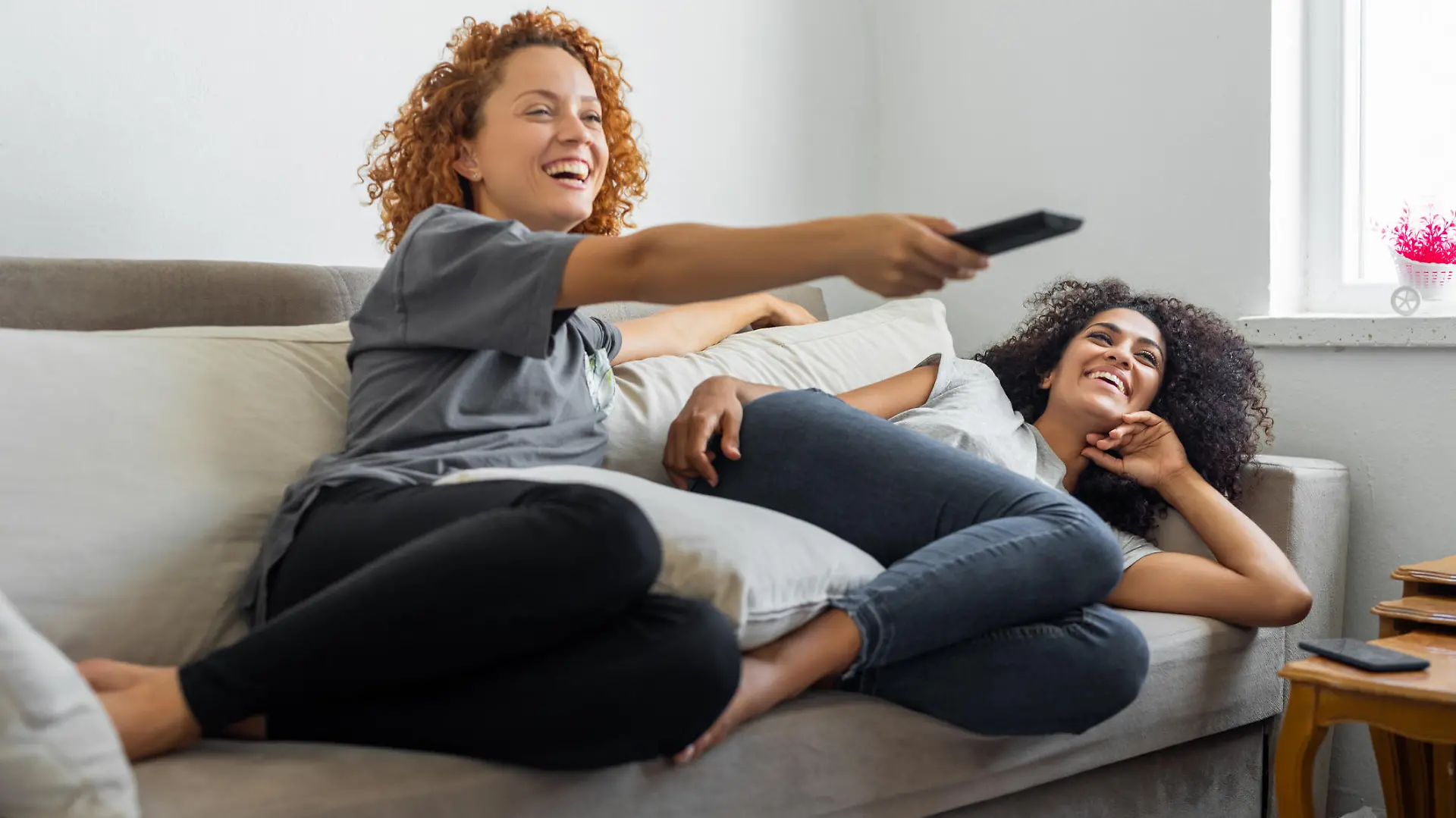 Girlfriends are watching their favorite tv show while sitting on the couch