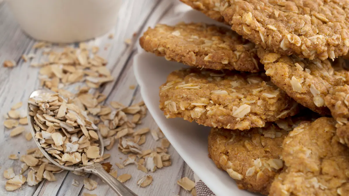 several oatmeal cookies in white plate with metal spoon filled with oatmill flakes