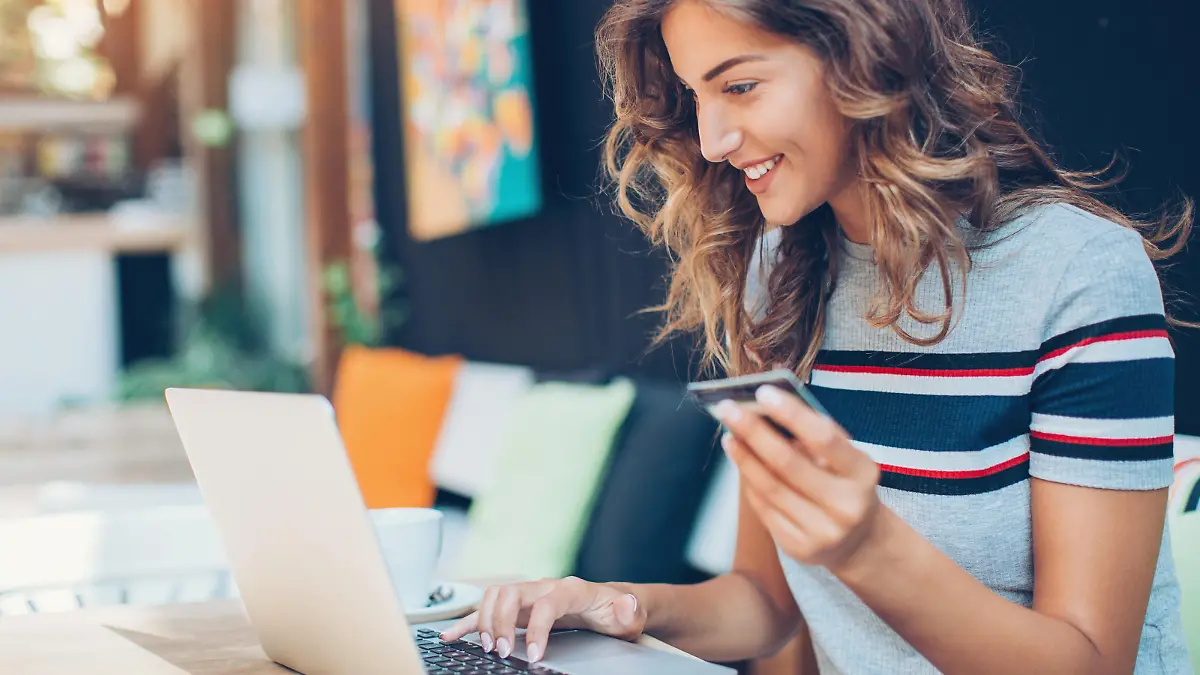 Beautiful young woman with credit card and laptop in cafe