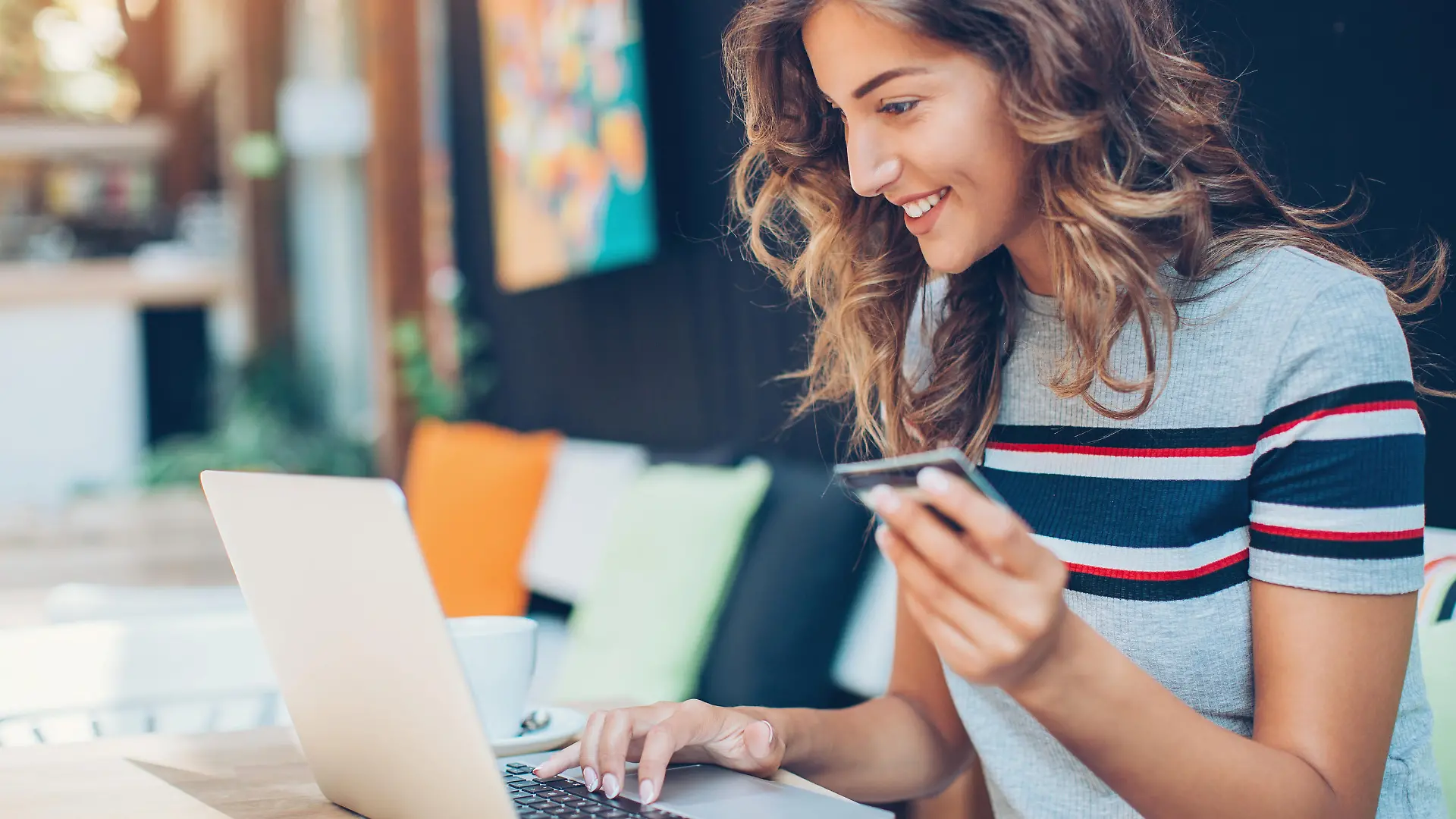 Beautiful young woman with credit card and laptop in cafe