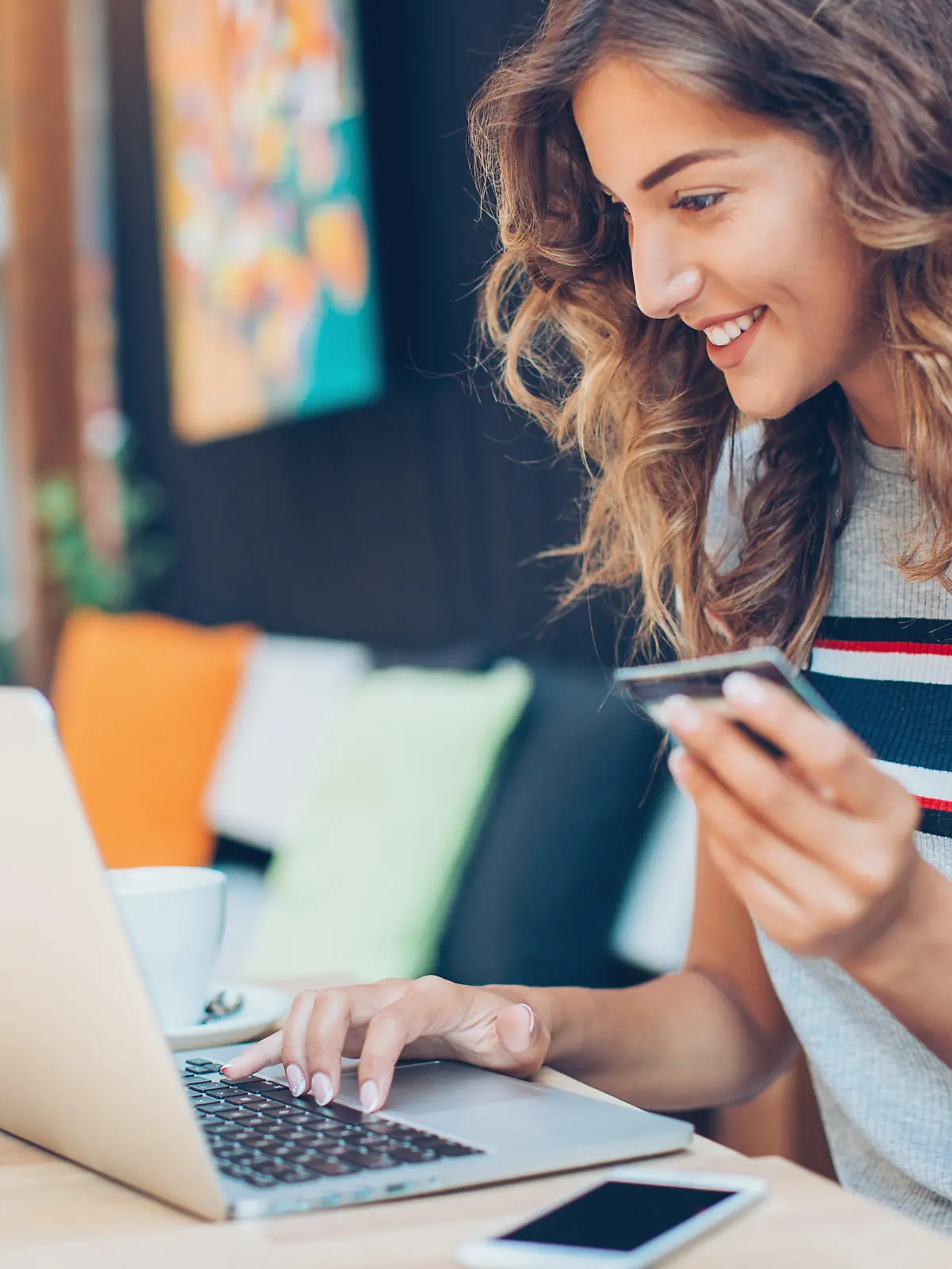 Beautiful young woman with credit card and laptop in cafe