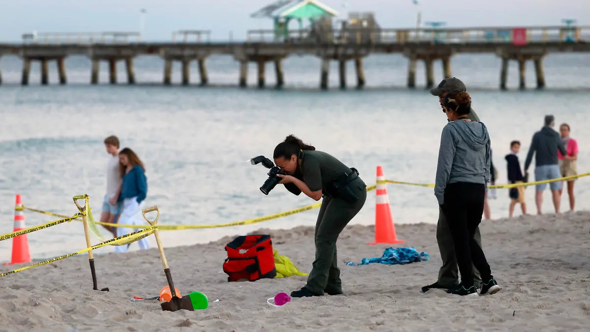 20.02.2024, USA, Lauderdale-by-the-Sea: Eine Polizistin macht am Strand von Lauderdale-by-the-Sea Fotos vom Tatort. Zwei Geschwisterkinder sind beim Buddeln am Strand von Lauderdale-by-the-Sea im Sand begraben worden. Eines der Kinder überlebte den Unfall nicht und wurde später im Krankenhaus für tot erklärt. Foto: Mike Stocker/South Florida Sun-Sentinel/AP/dpa +++ dpa-Bildfunk +++