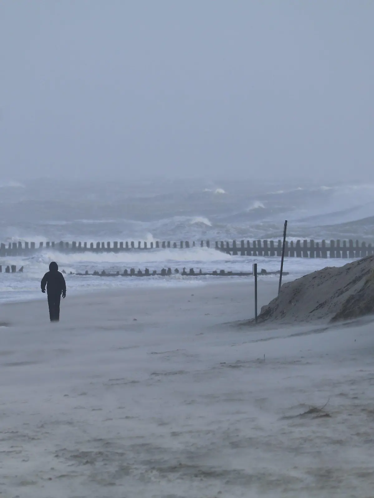 ARCHIV - 24.01.2024, Niedersachsen, Norderney: Ein Spaziergänger geht bei stürmischem Wetter am Strand der Insel Norderney.  (zu dpa: «Wetterdienst kündigt Sturm in Niedersachsen an») Foto: Volker Bartels/dpa +++ dpa-Bildfunk +++