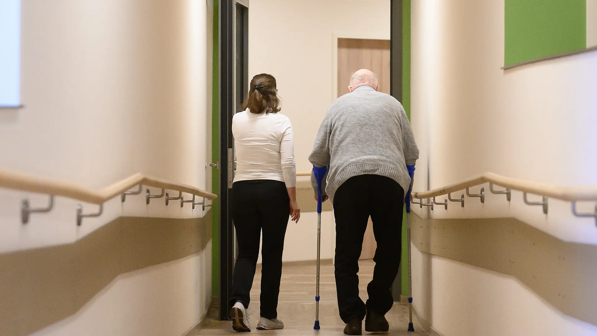 ARCHIV - 22.01.2024, Hessen, Willingen: Ein Patient geht mit Krücken durch einen Flur im Pflegehotel Willingen. Das Pflegehotel Willingen bietet Tagespflege an allen Wochentagen an. (zu dpa: «Hessen will mehr Entlastung in der Pflege schaffen») Foto: Swen Pförtner/dpa +++ dpa-Bildfunk +++