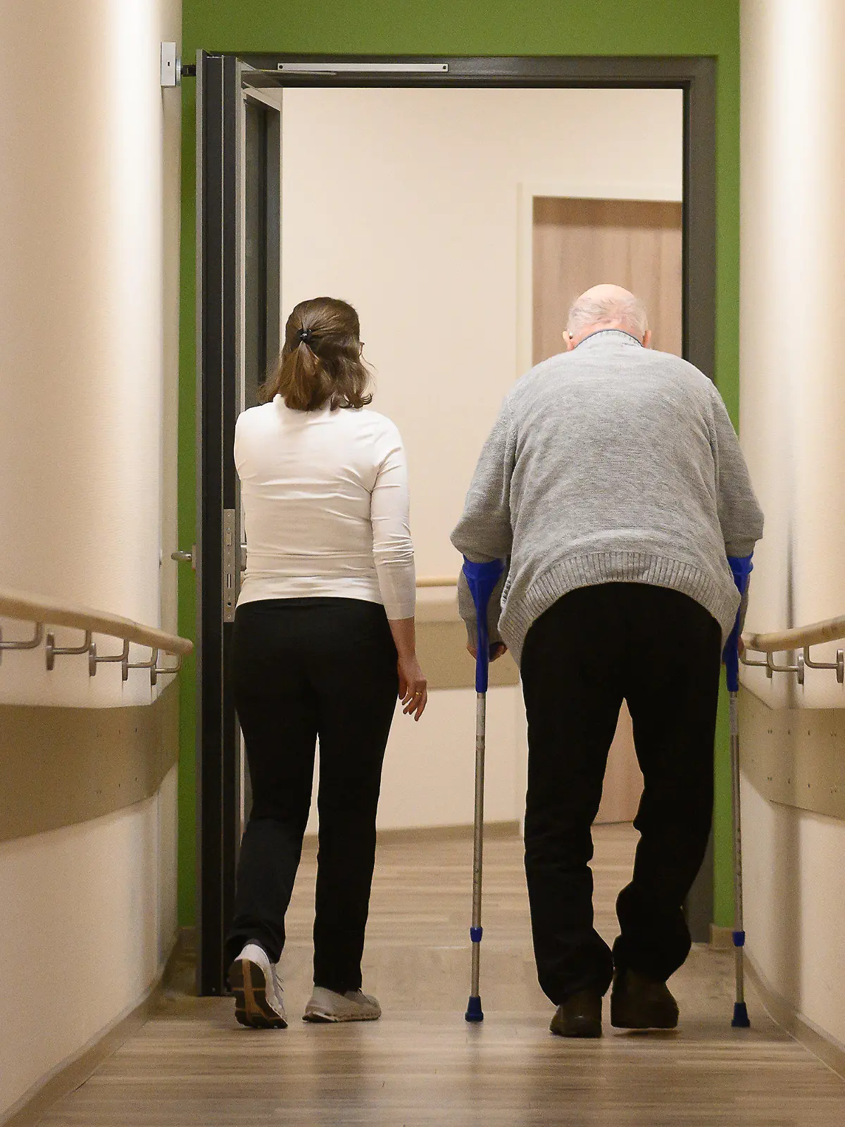 ARCHIV - 22.01.2024, Hessen, Willingen: Ein Patient geht mit Krücken durch einen Flur im Pflegehotel Willingen. Das Pflegehotel Willingen bietet Tagespflege an allen Wochentagen an. (zu dpa: «Hessen will mehr Entlastung in der Pflege schaffen») Foto: Swen Pförtner/dpa +++ dpa-Bildfunk +++