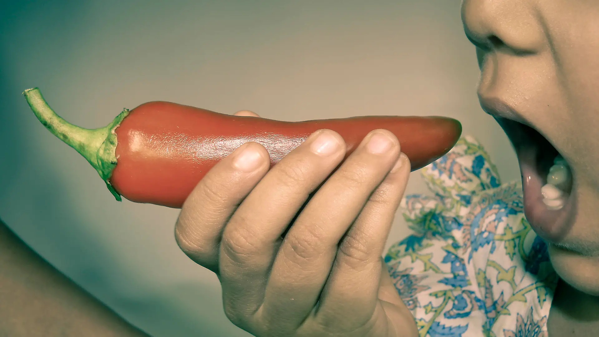 Small Girl holding chili in her mouth
