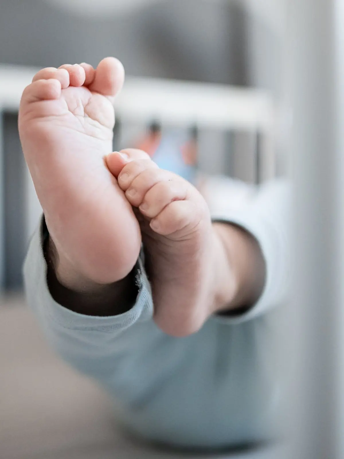 Die Füße eines Babys sind in einem Kinderbett zu sehen.
