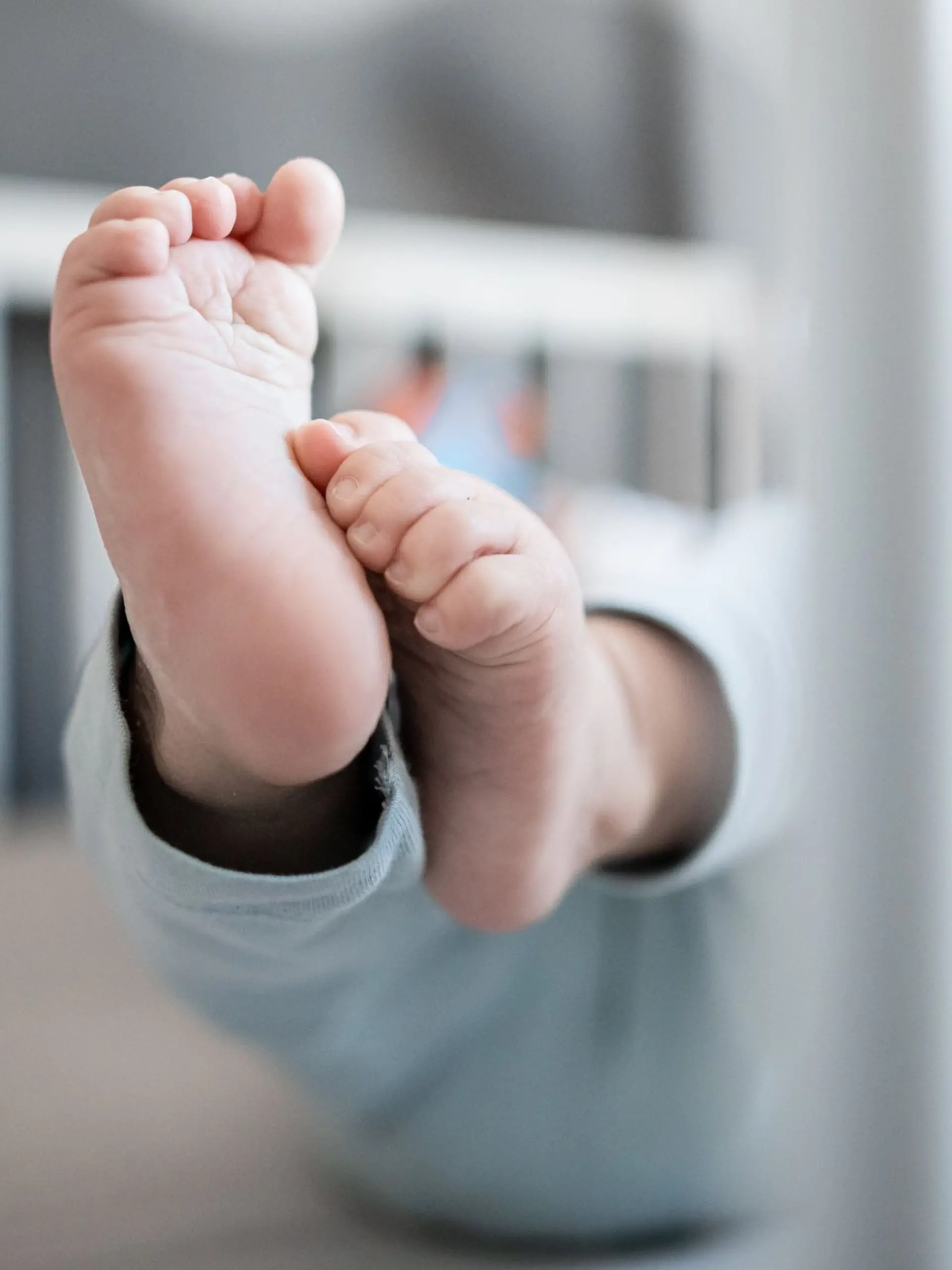 Die Füße eines Babys sind in einem Kinderbett zu sehen.