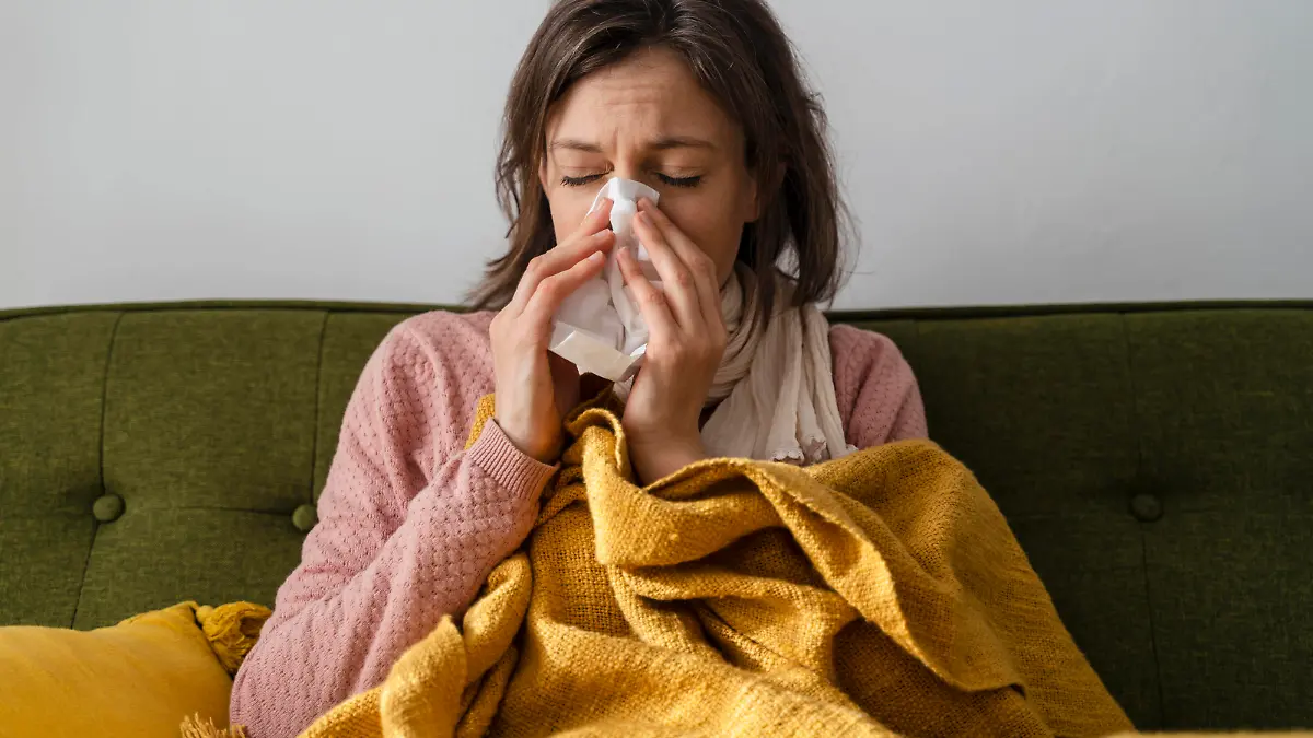 Sick woman blowing nose in facial tissue sitting on sofa at home model released, Symbolfoto property released, DIGF17732