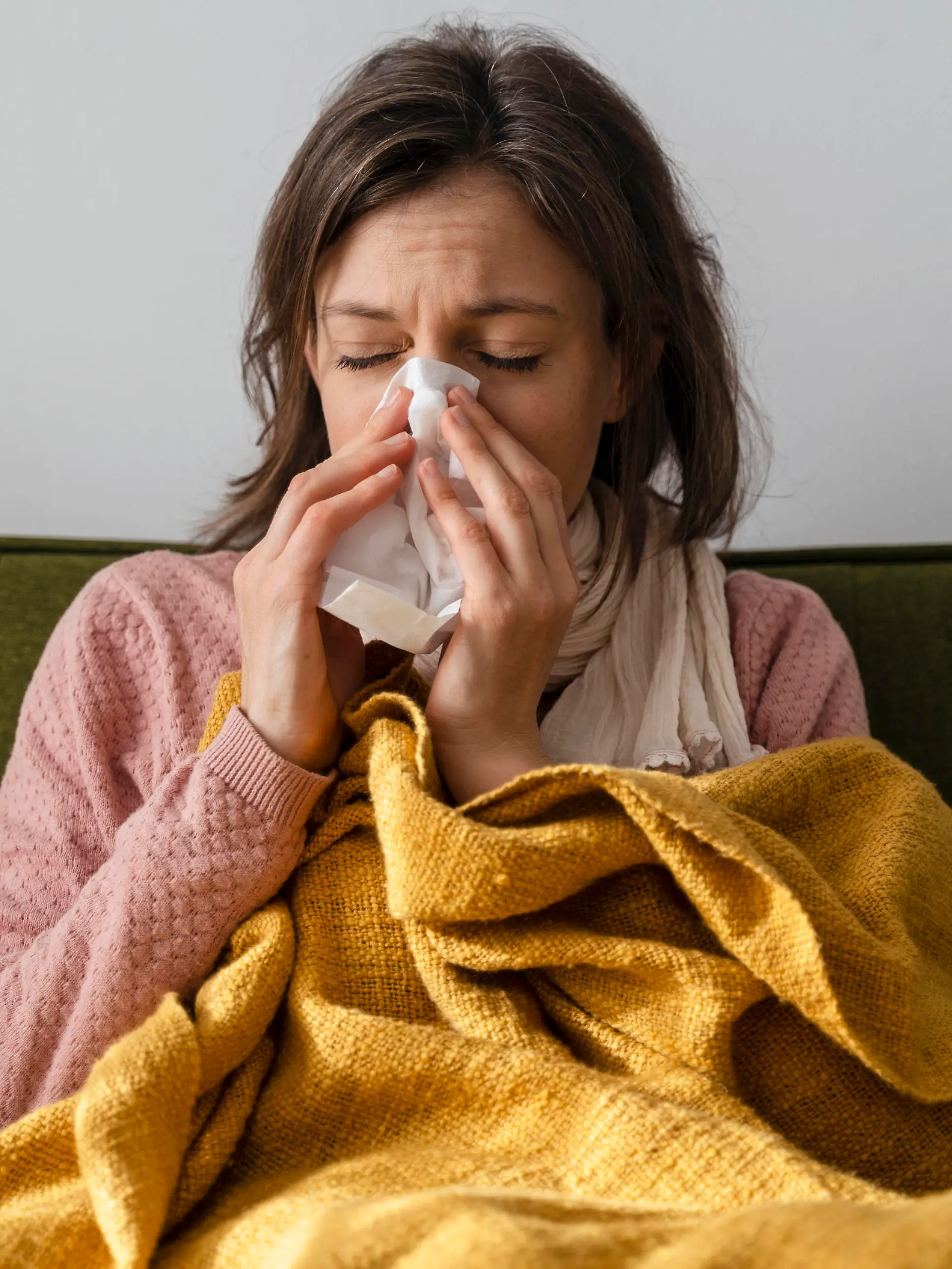 Sick woman blowing nose in facial tissue sitting on sofa at home model released, Symbolfoto property released, DIGF17732